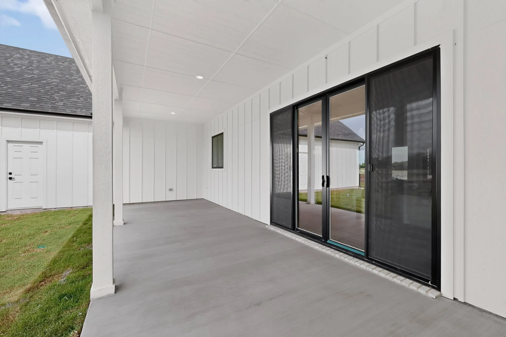 Spacious covered patio featuring a concrete surface, recessed lighting, and white board-and-batten siding