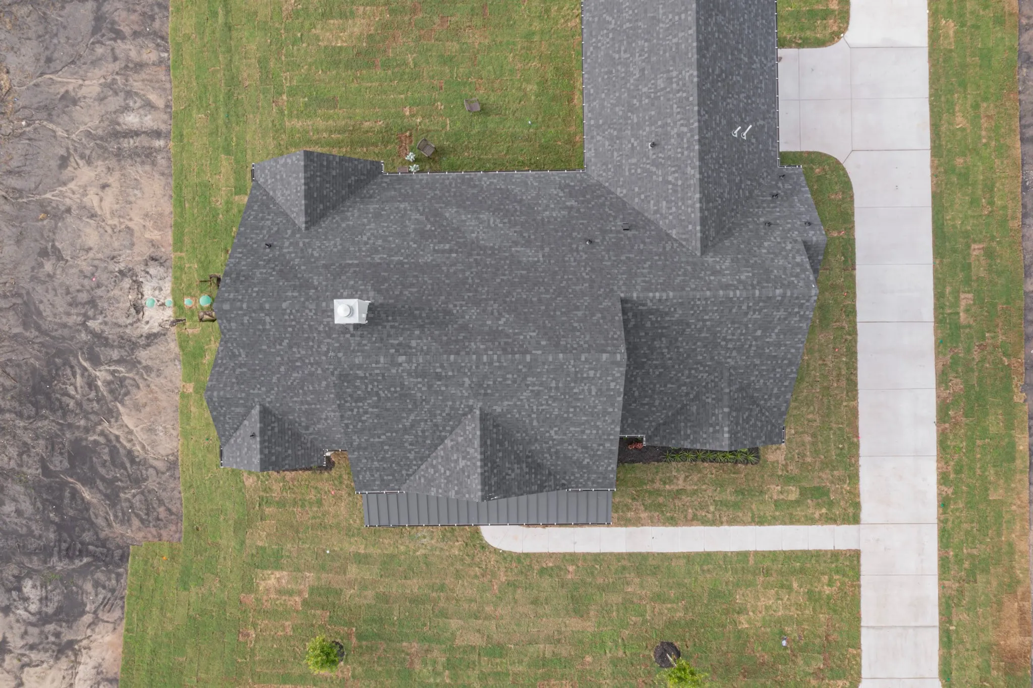 Asphalt shingle roofline with multiple gables and a central chimney