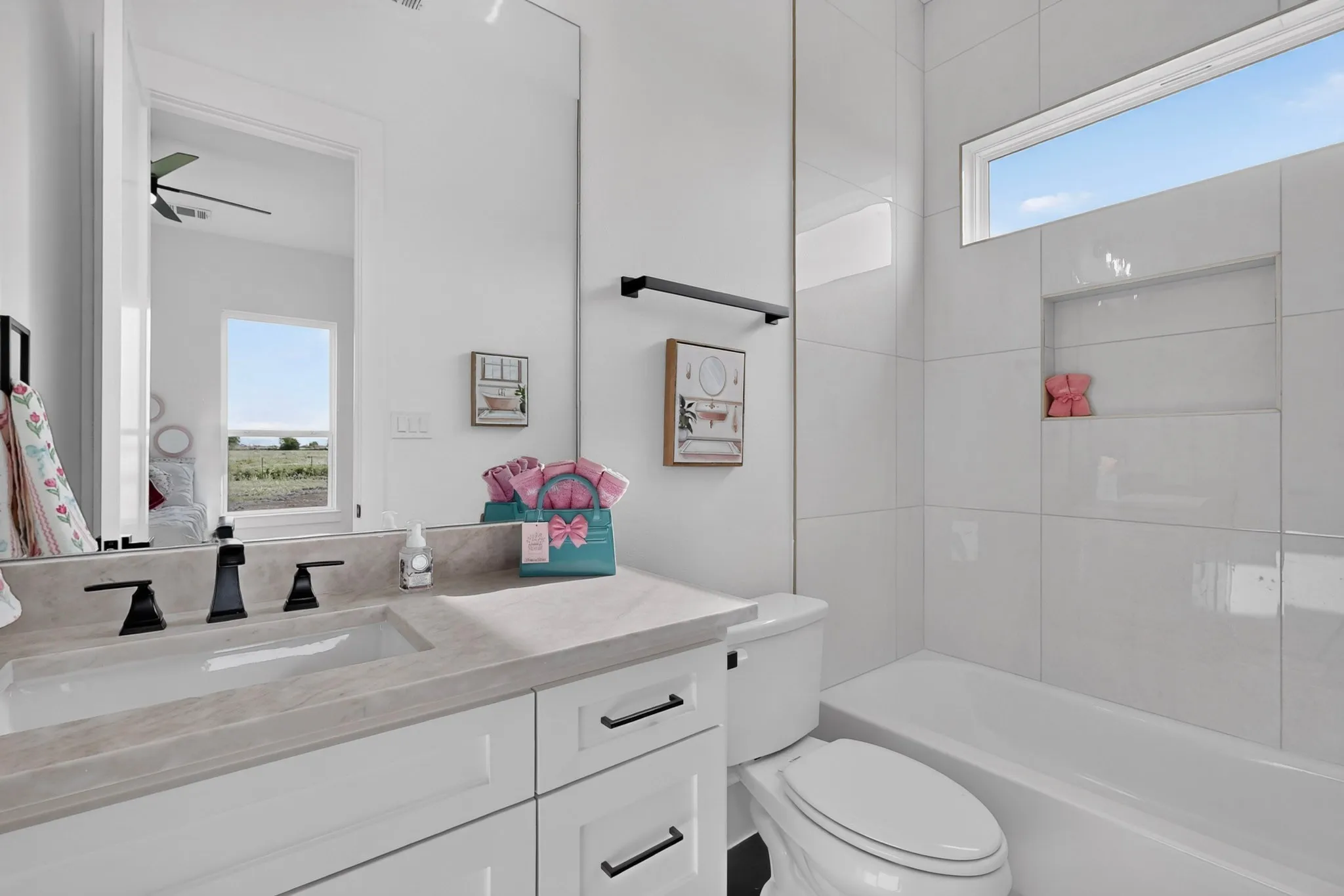 Modern bathroom featuring a single vanity with an integrated sink, matte black faucet, and white cabinetry with black hardware