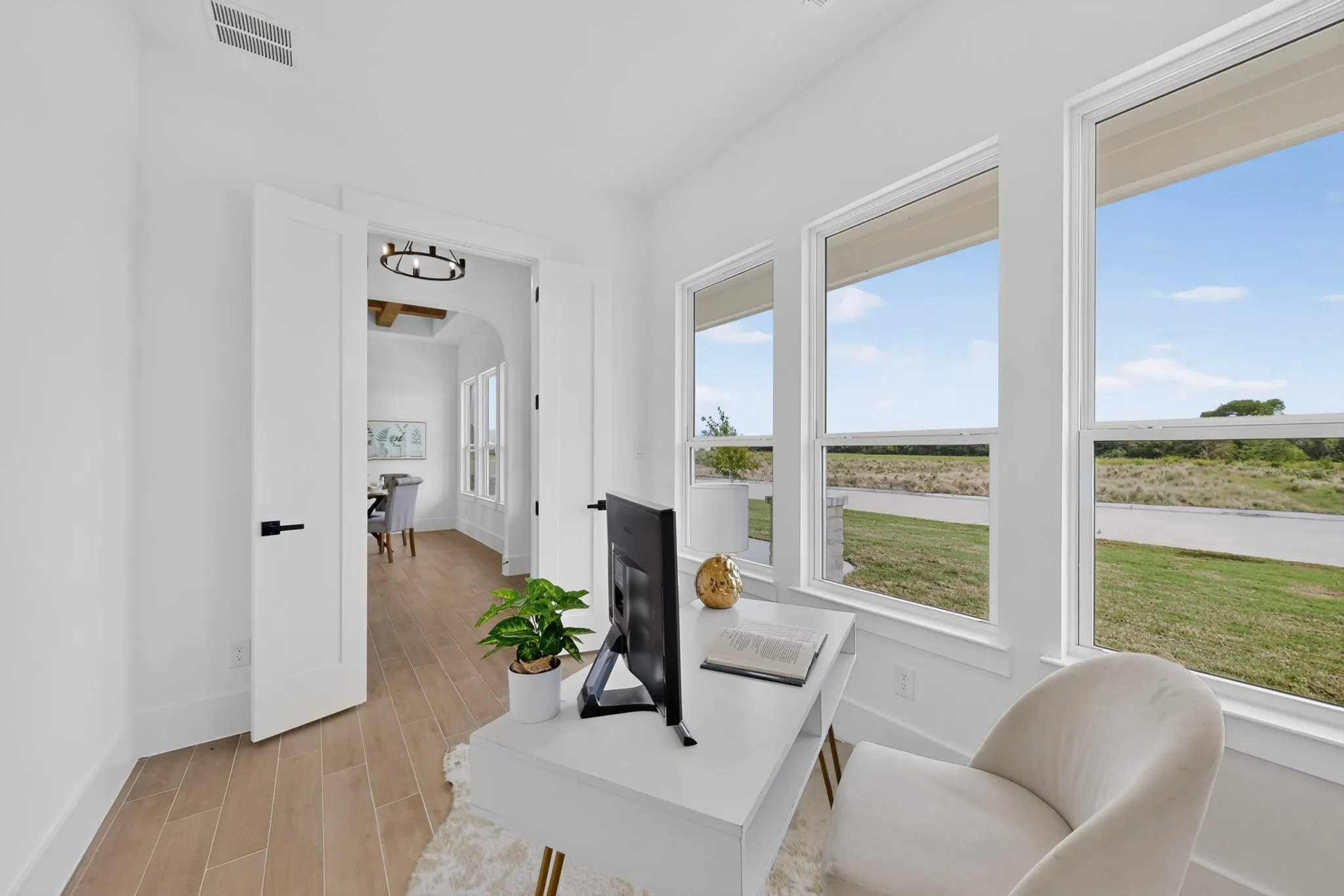Bright room featuring wood-finish flooring, white walls, and a pair of double doors with matte black hardware