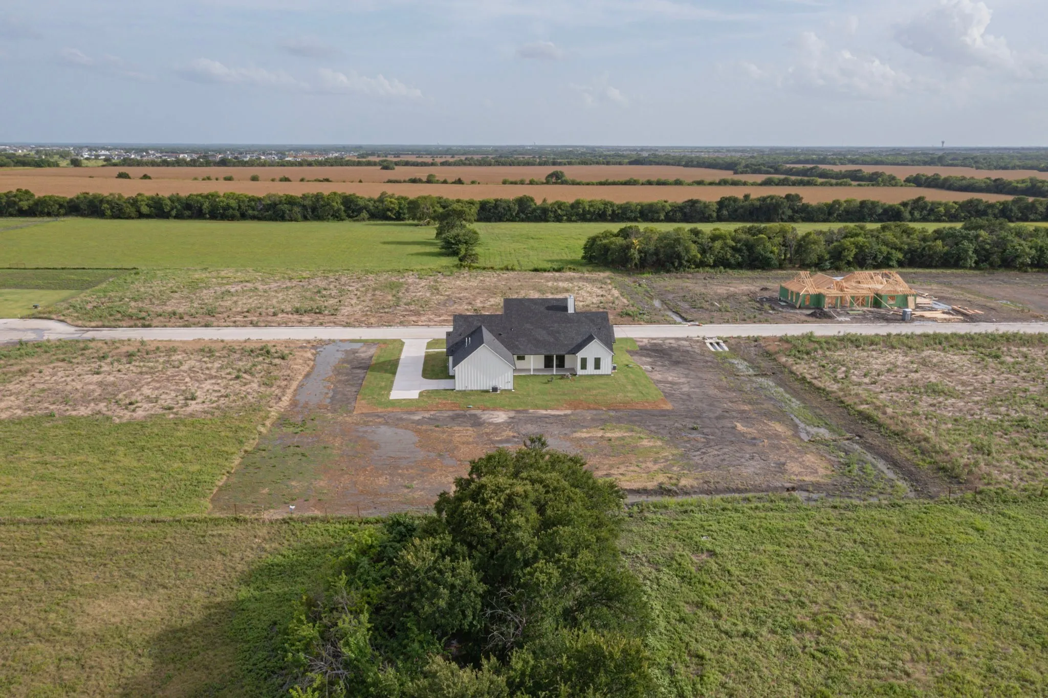 Modern farmhouse architecture with a dark shingle roof and light-colored siding