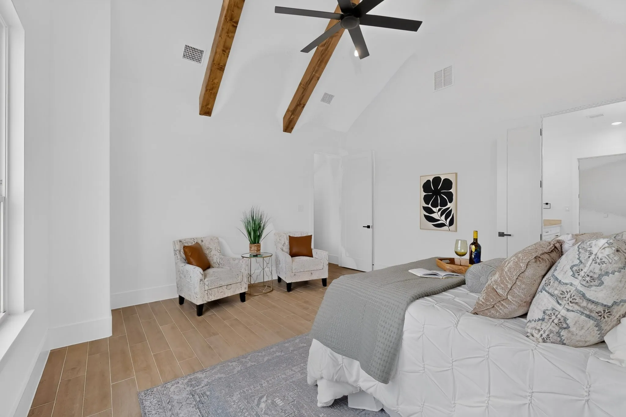 Vaulted white ceilings featuring exposed wood beams and a contemporary ceiling fan