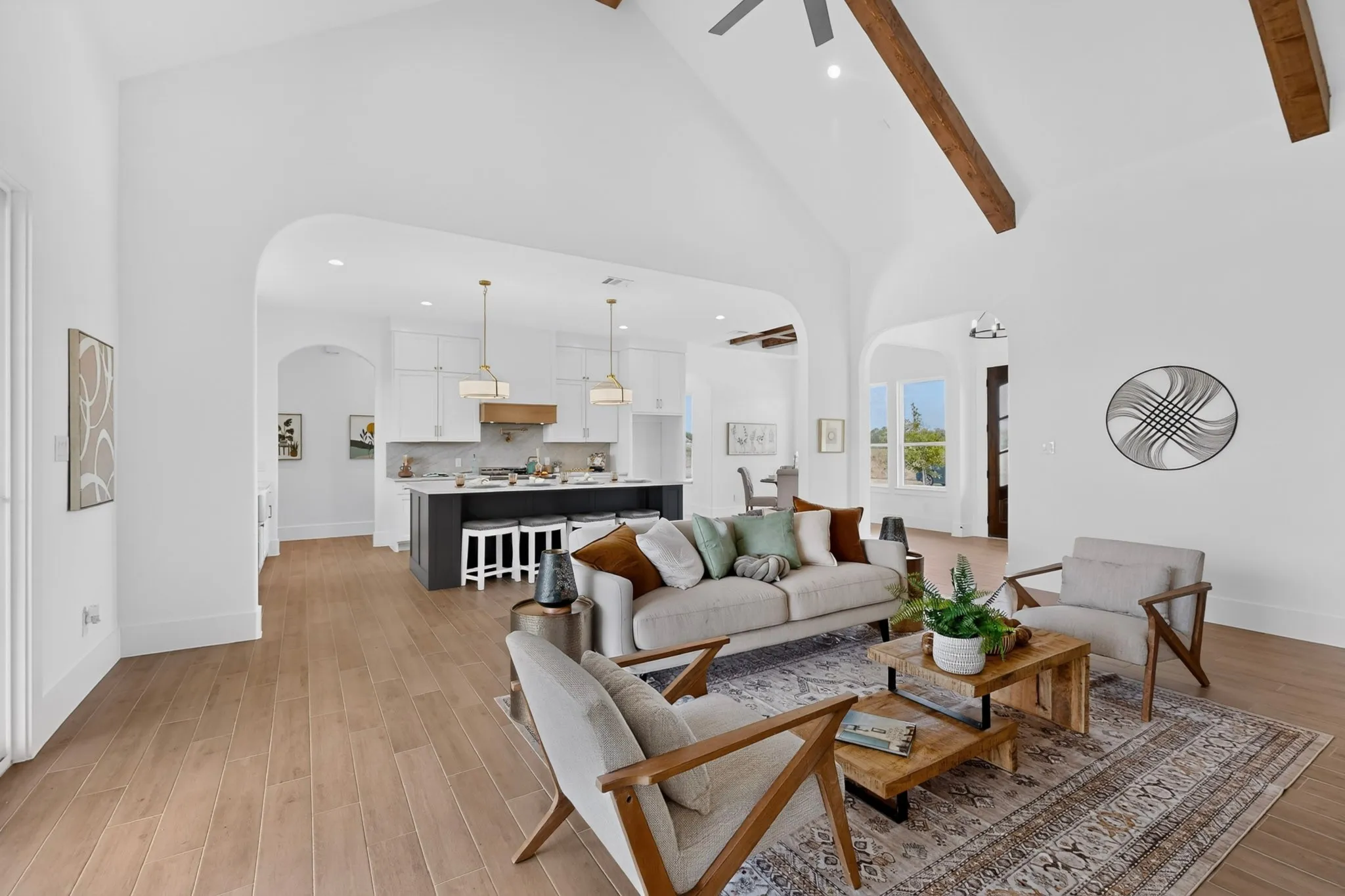 Vaulted ceiling with exposed wood beams, wood-finish flooring, and arched doorways