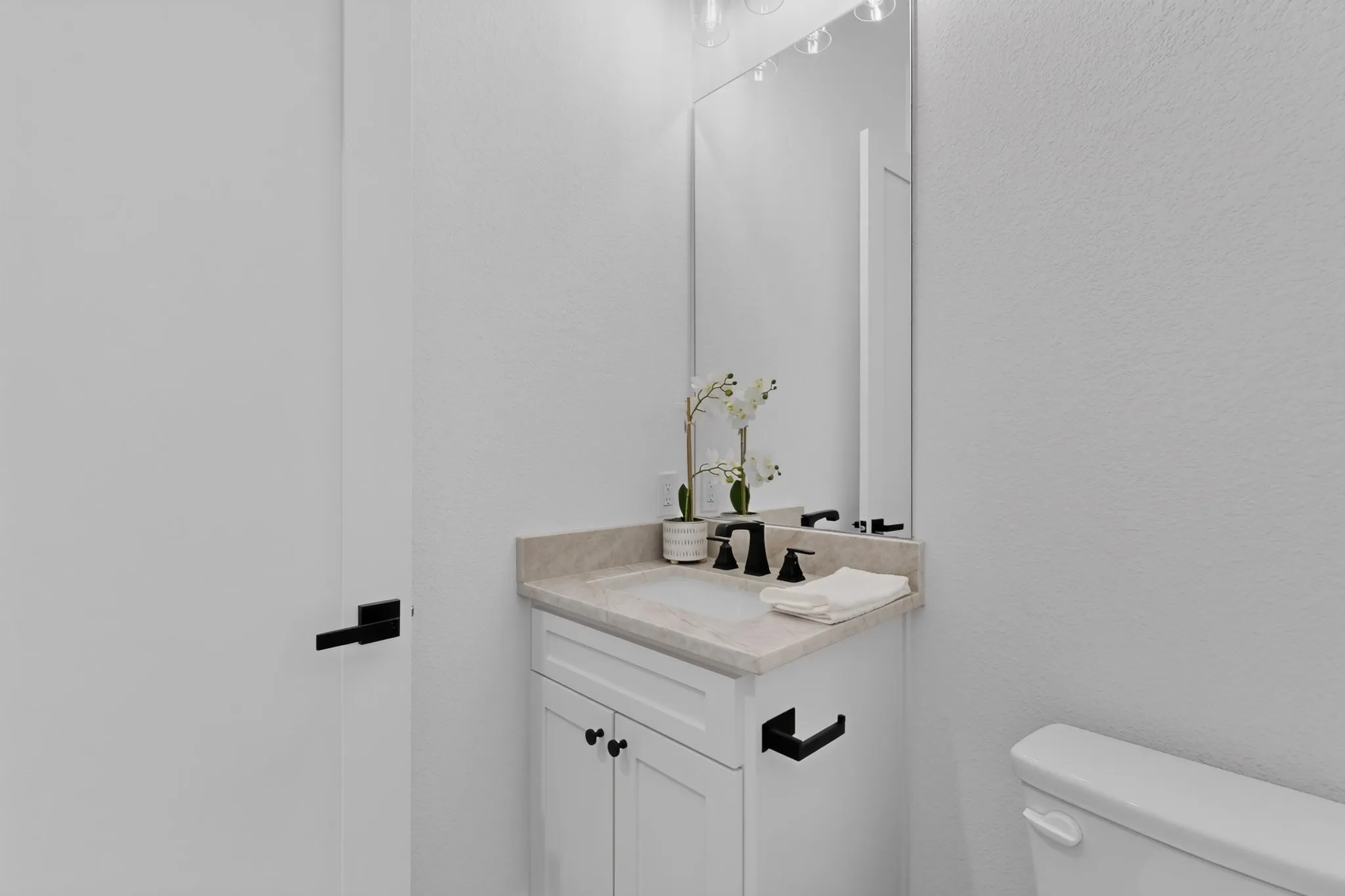 White vanity with cabinet storage, light-toned countertop, and integrated sink