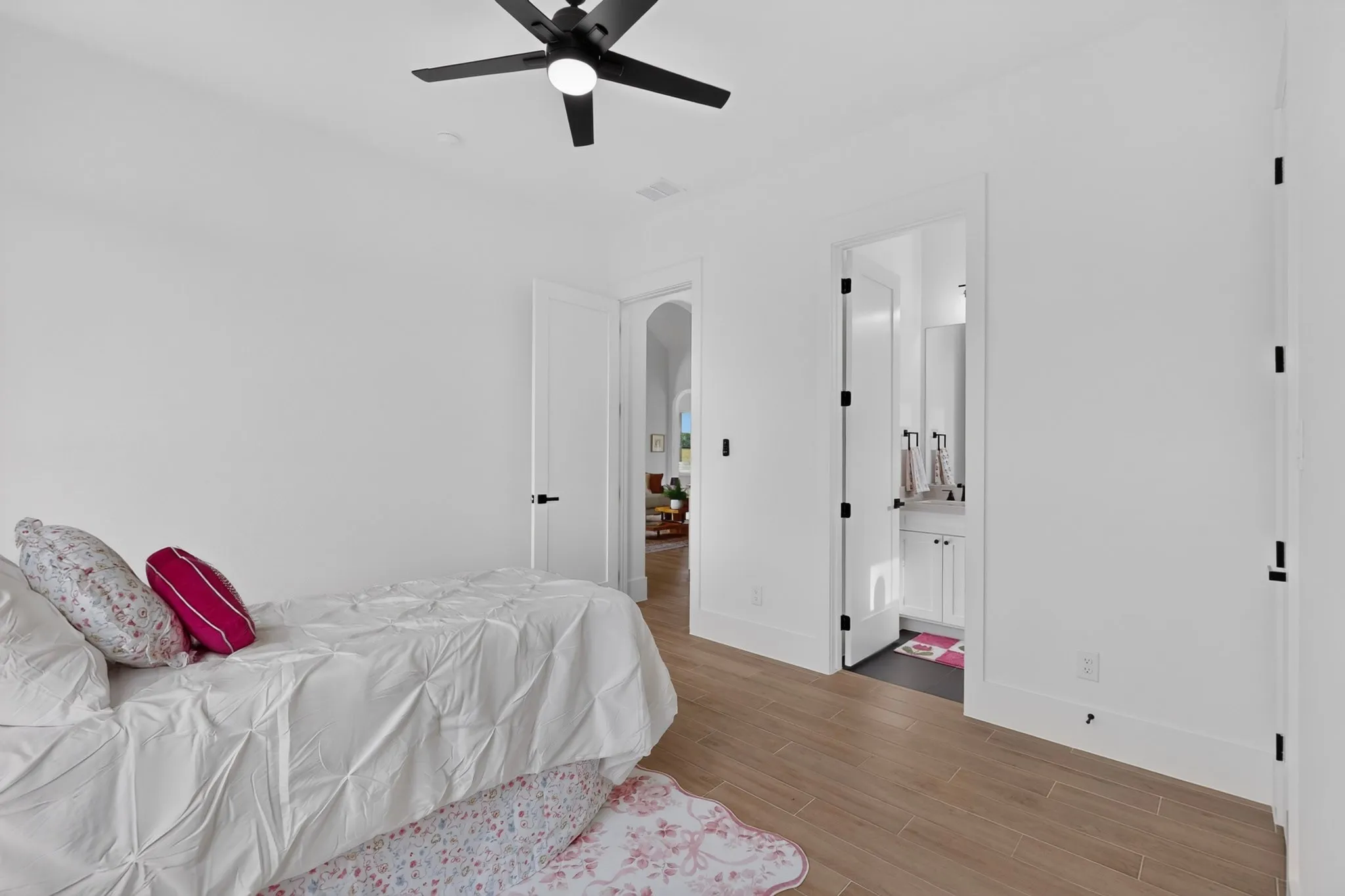 Bright interior featuring wood-finish flooring, white walls, and a black ceiling fan