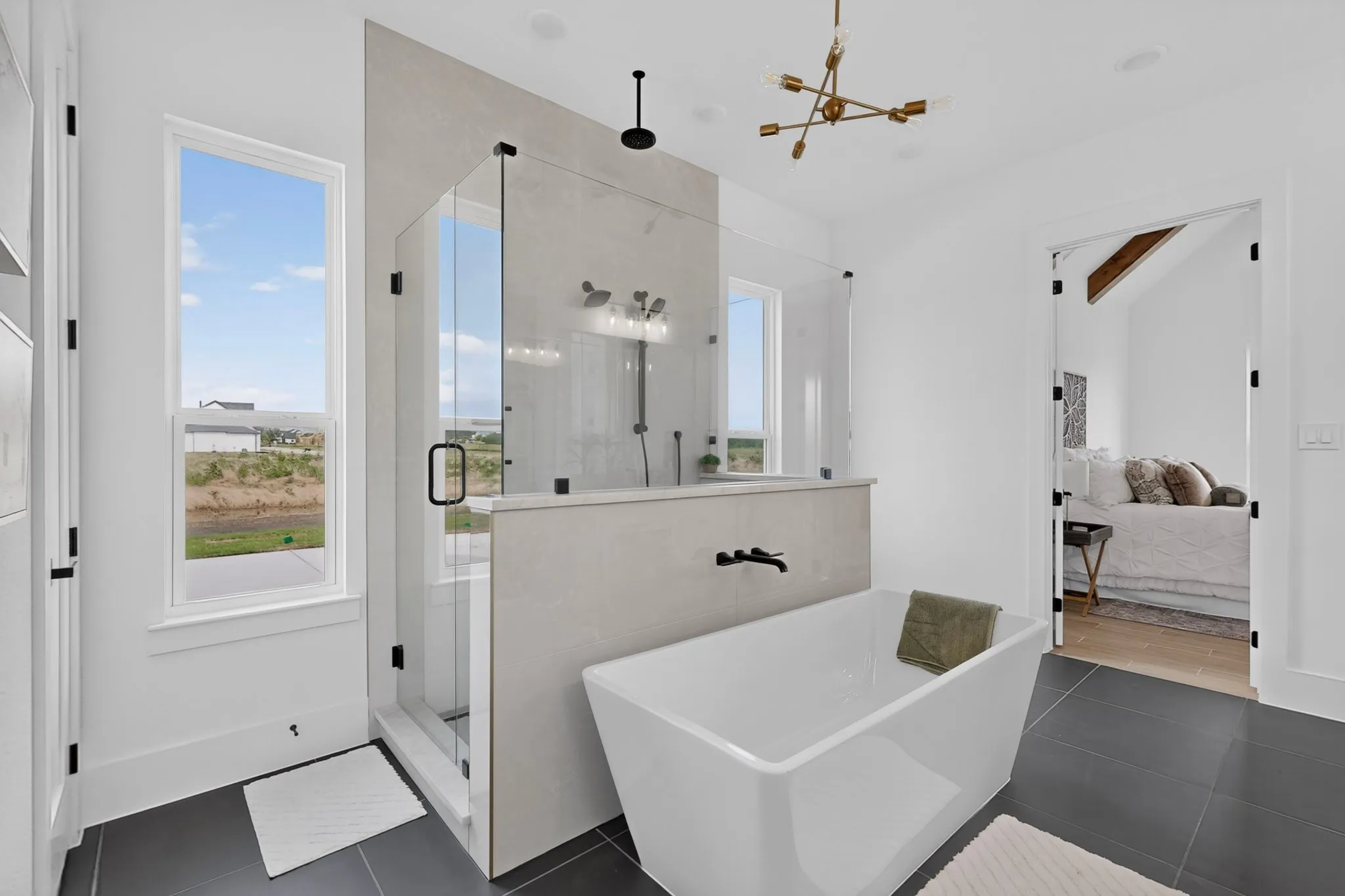 Modern bathroom featuring a freestanding soaking tub, a spacious glass-enclosed shower with black fixtures, and dark tile flooring