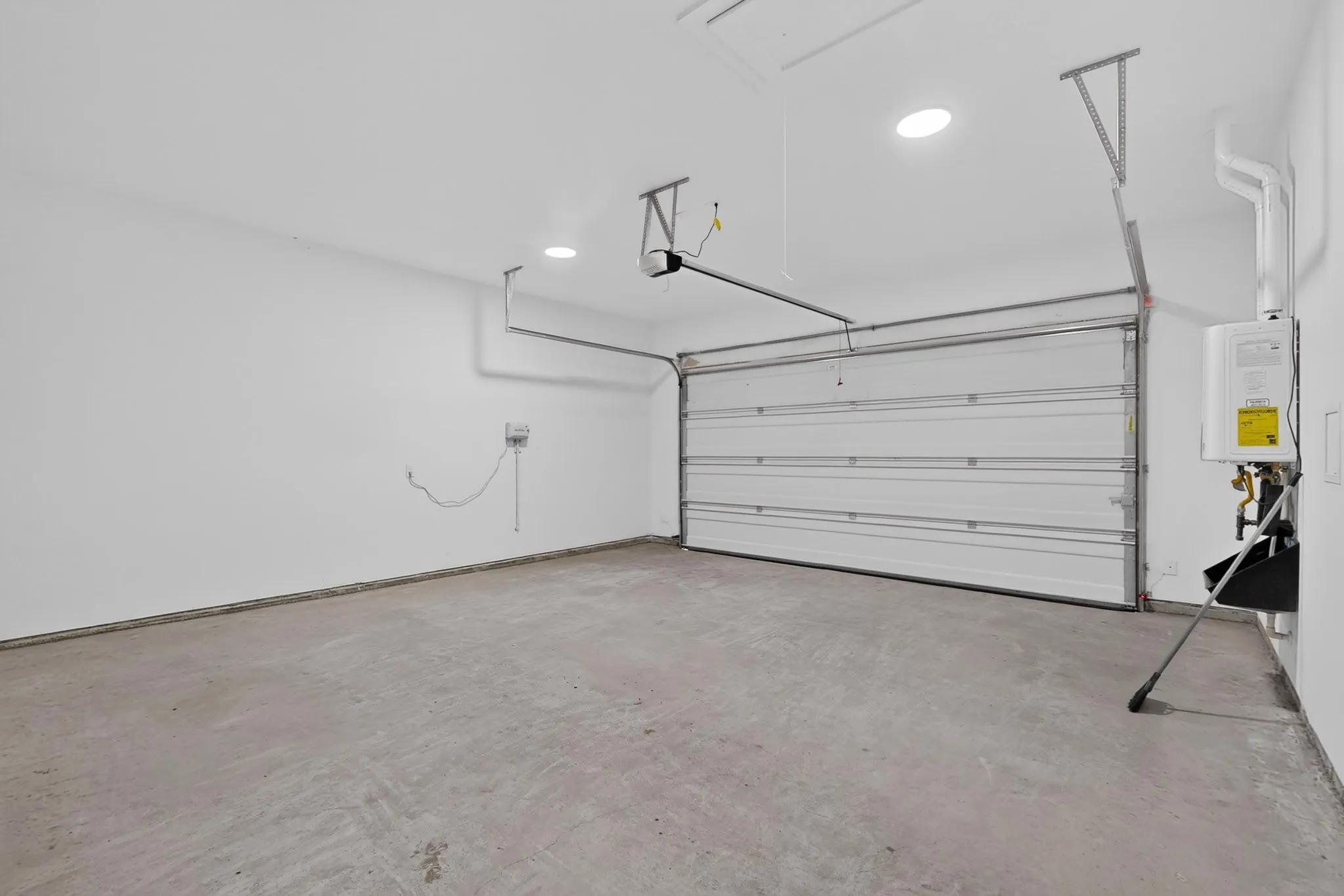 Spacious garage featuring a concrete floor, white walls, and an automatic garage door opener