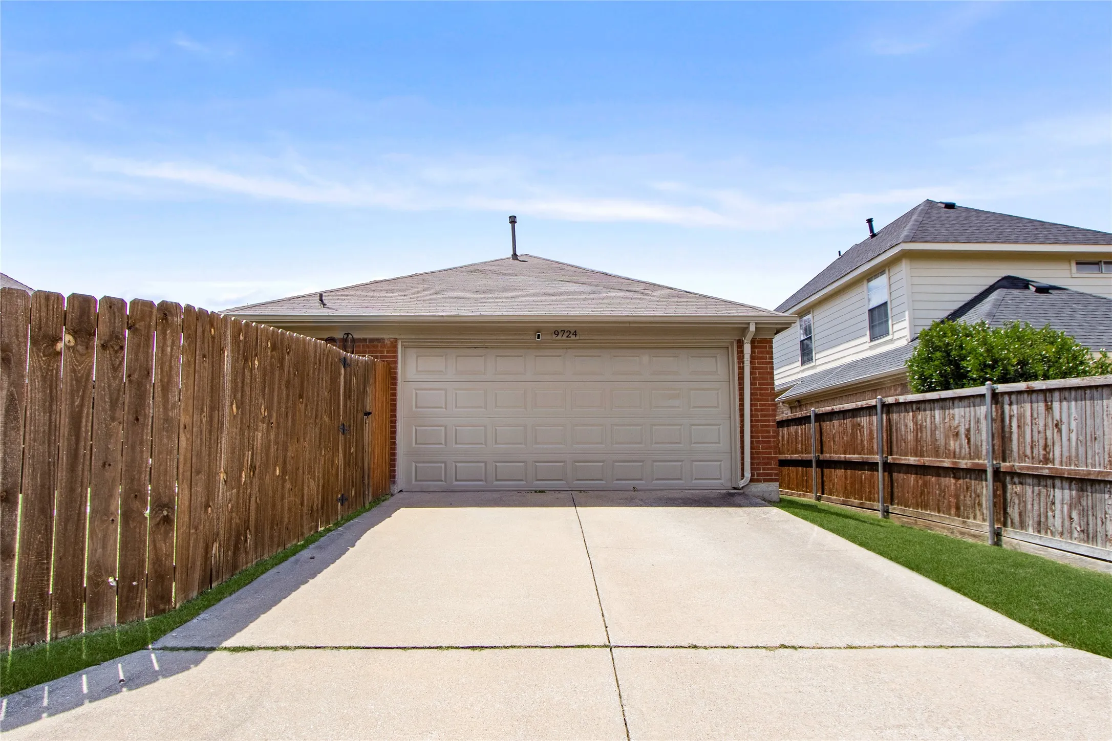 Attached garage with a panel door, concrete driveway, and wood privacy fencing