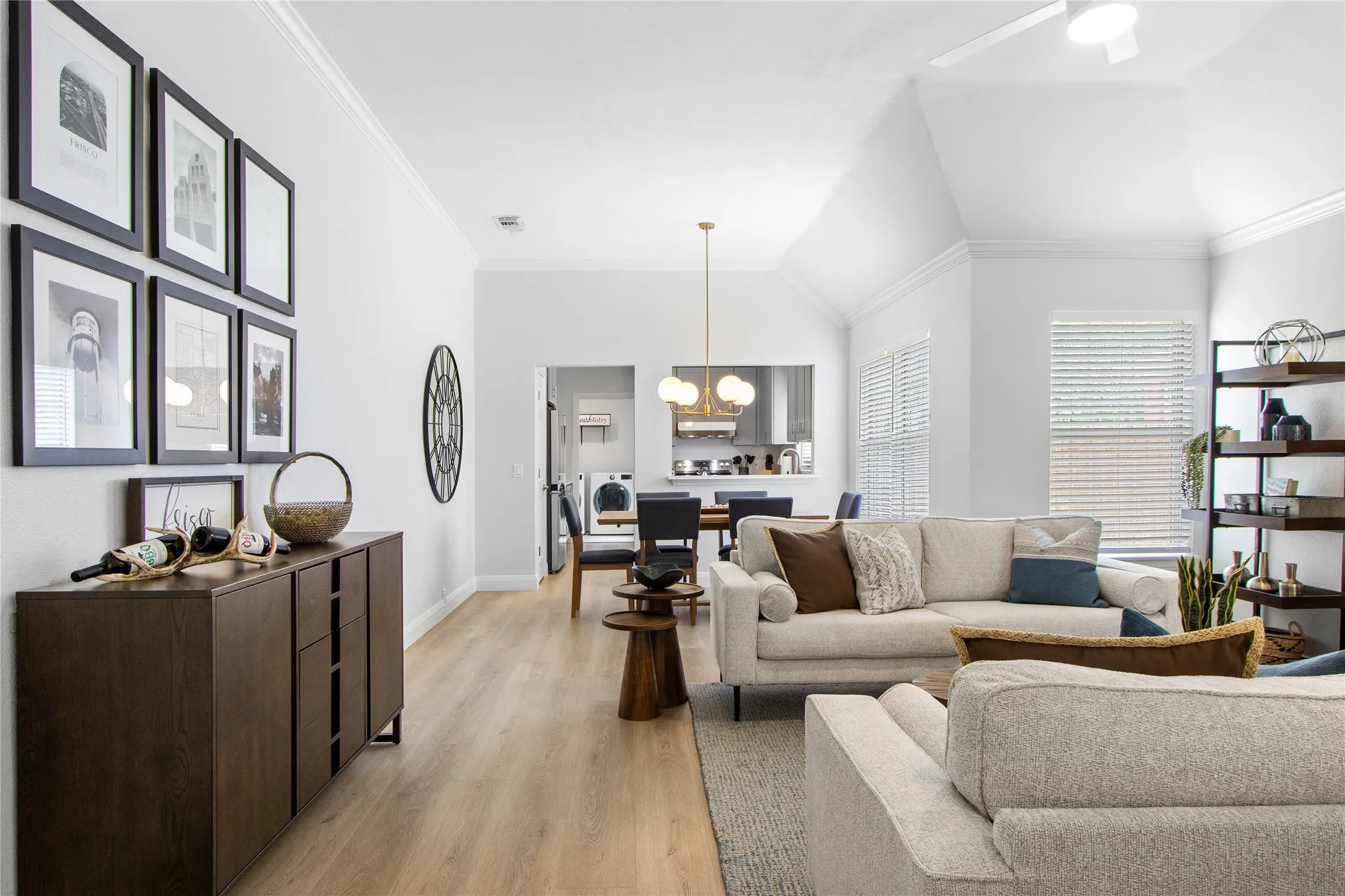 Bright living area with vaulted ceilings, crown molding, wood-finish flooring, and a ceiling fan
