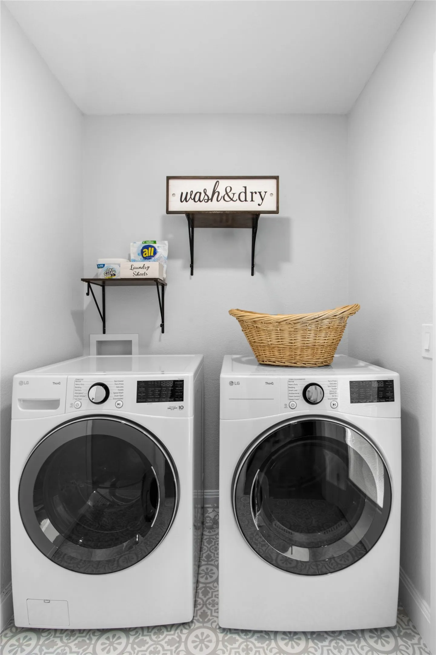 Dedicated laundry area featuring a patterned floor, light-toned walls, and a built-in wall shelf