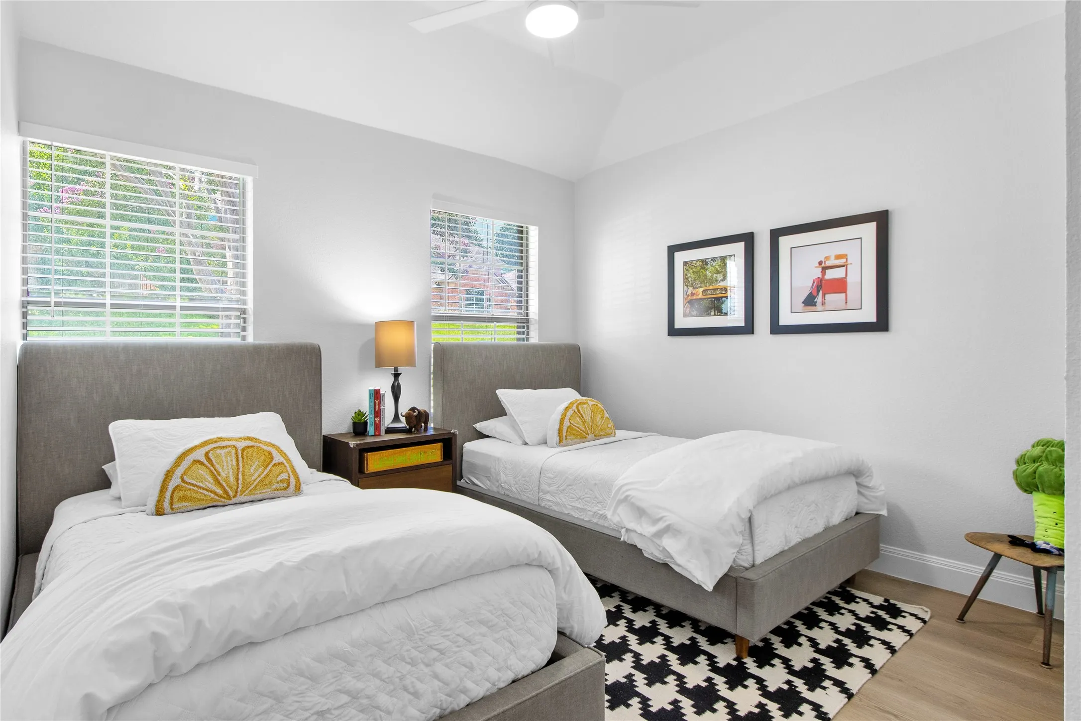Spacious room featuring vaulted ceilings, wood-finish flooring, and two large windows with blinds