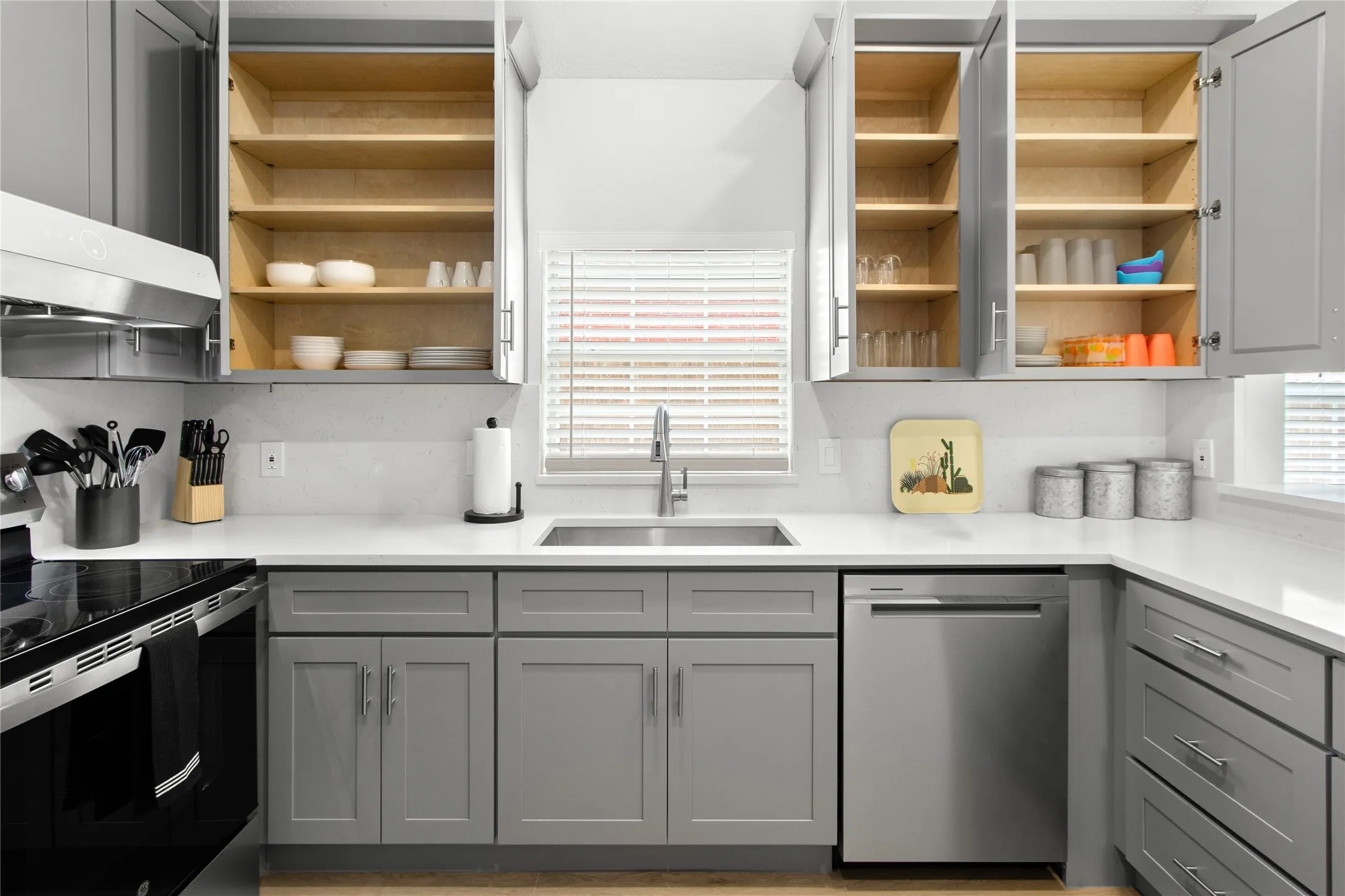 Modern kitchen featuring gray cabinetry, stainless steel appliances, a single basin sink, and white countertops