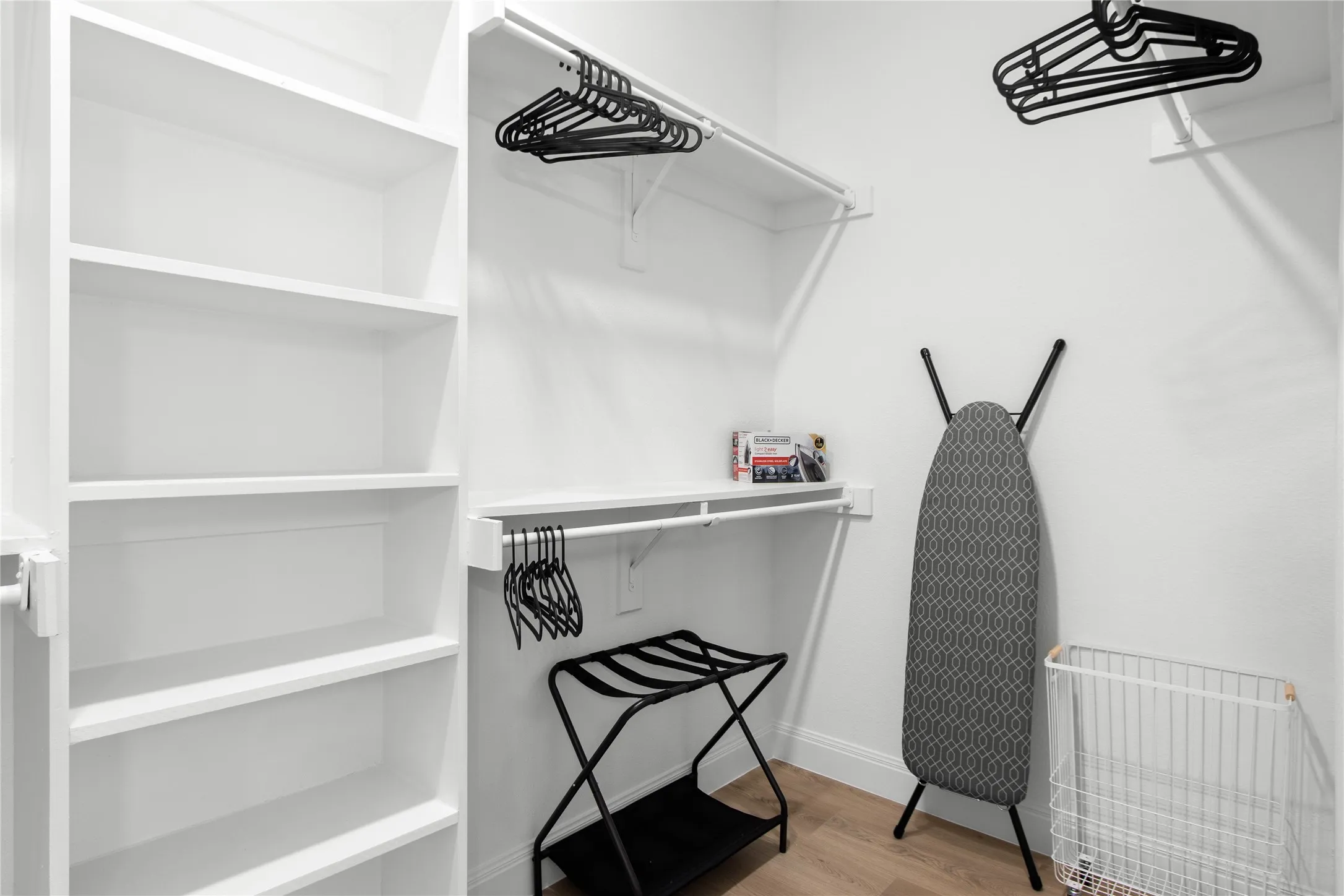 Custom closet system featuring built-in shelving, multiple hanging rods, and wood-finish flooring