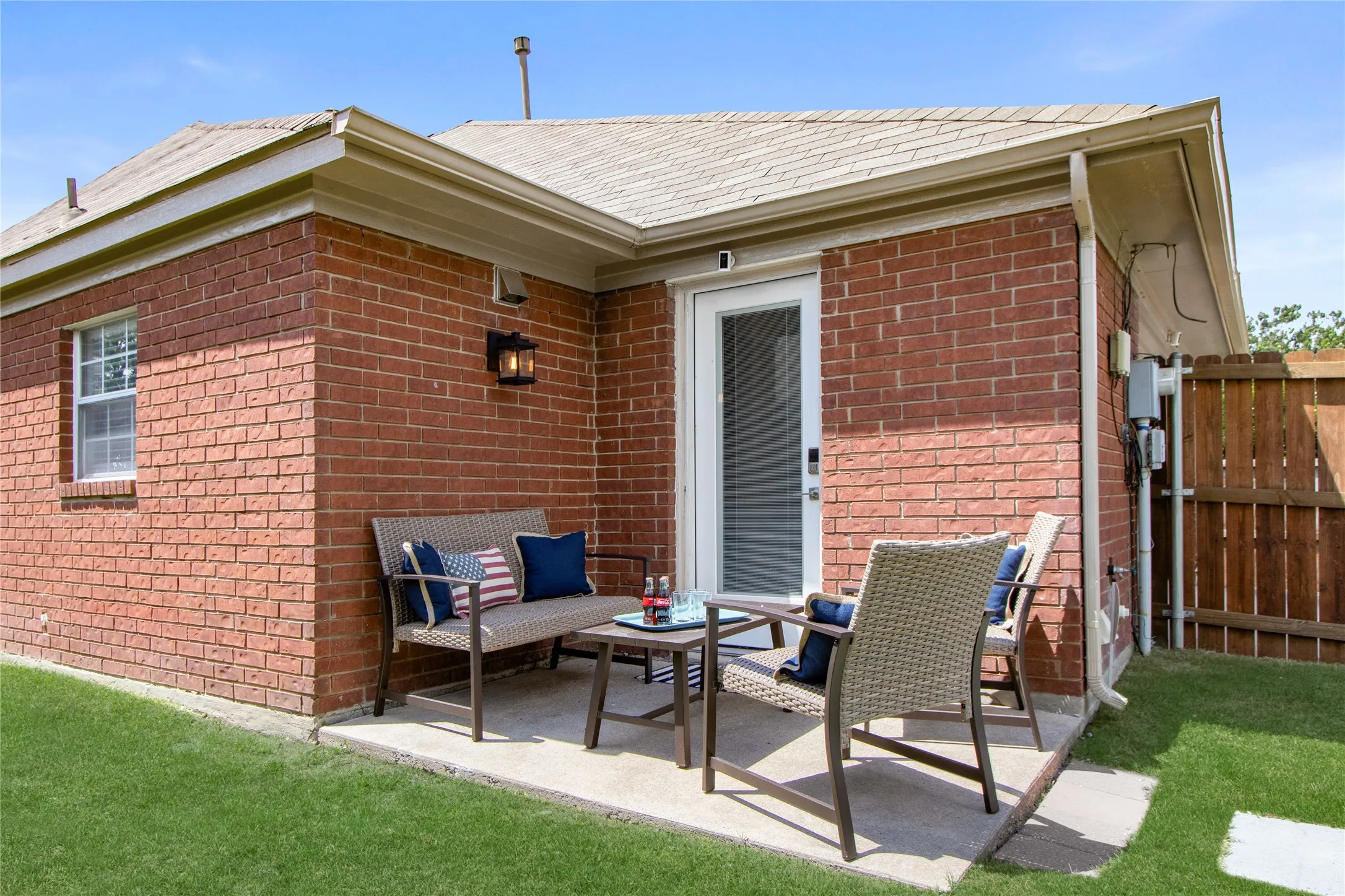 Brick exterior featuring a concrete patio, white-framed window, and outdoor wall sconce