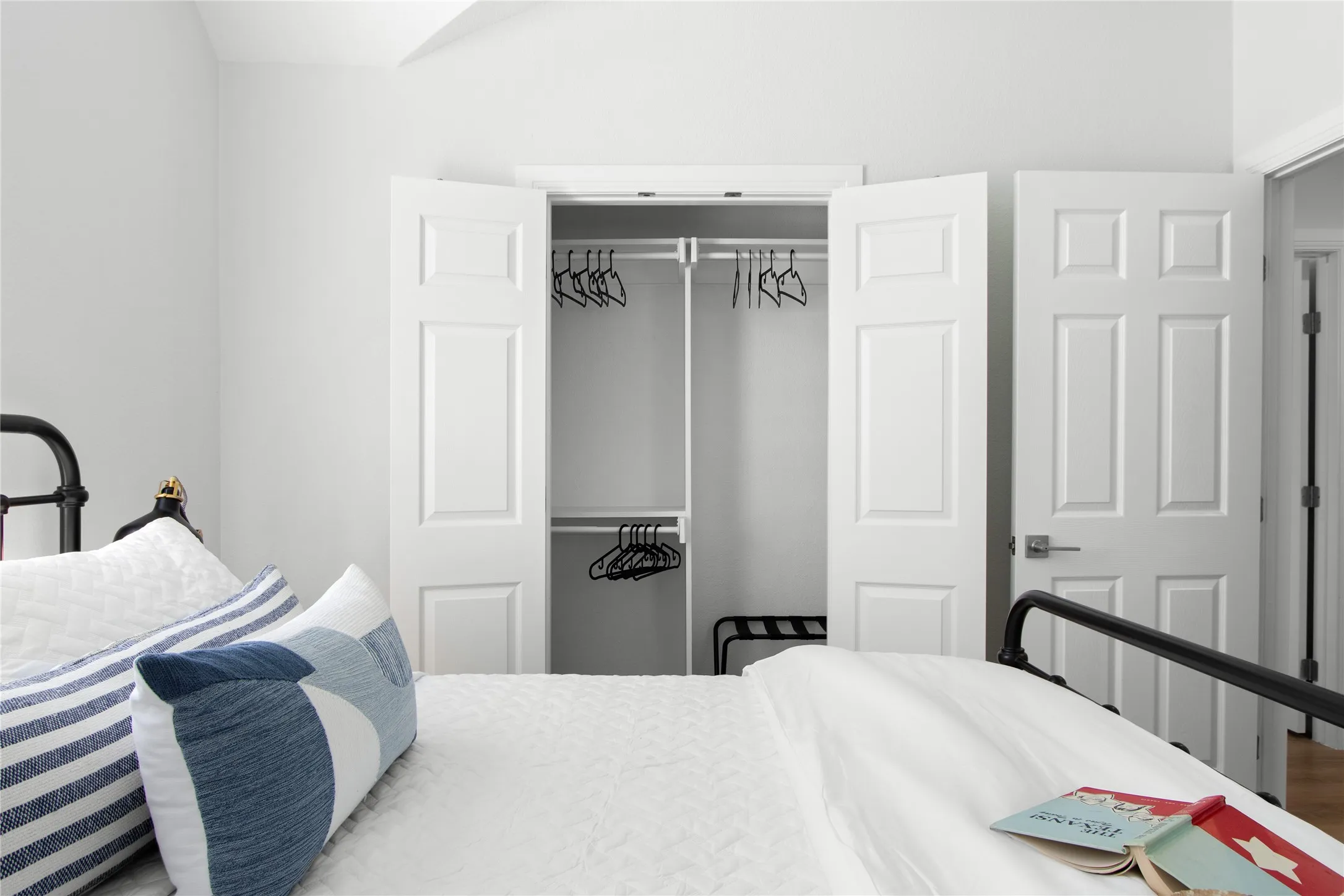 Bright interior bedroom featuring a closet with bi-fold doors, interior shelving, and a hanging rod