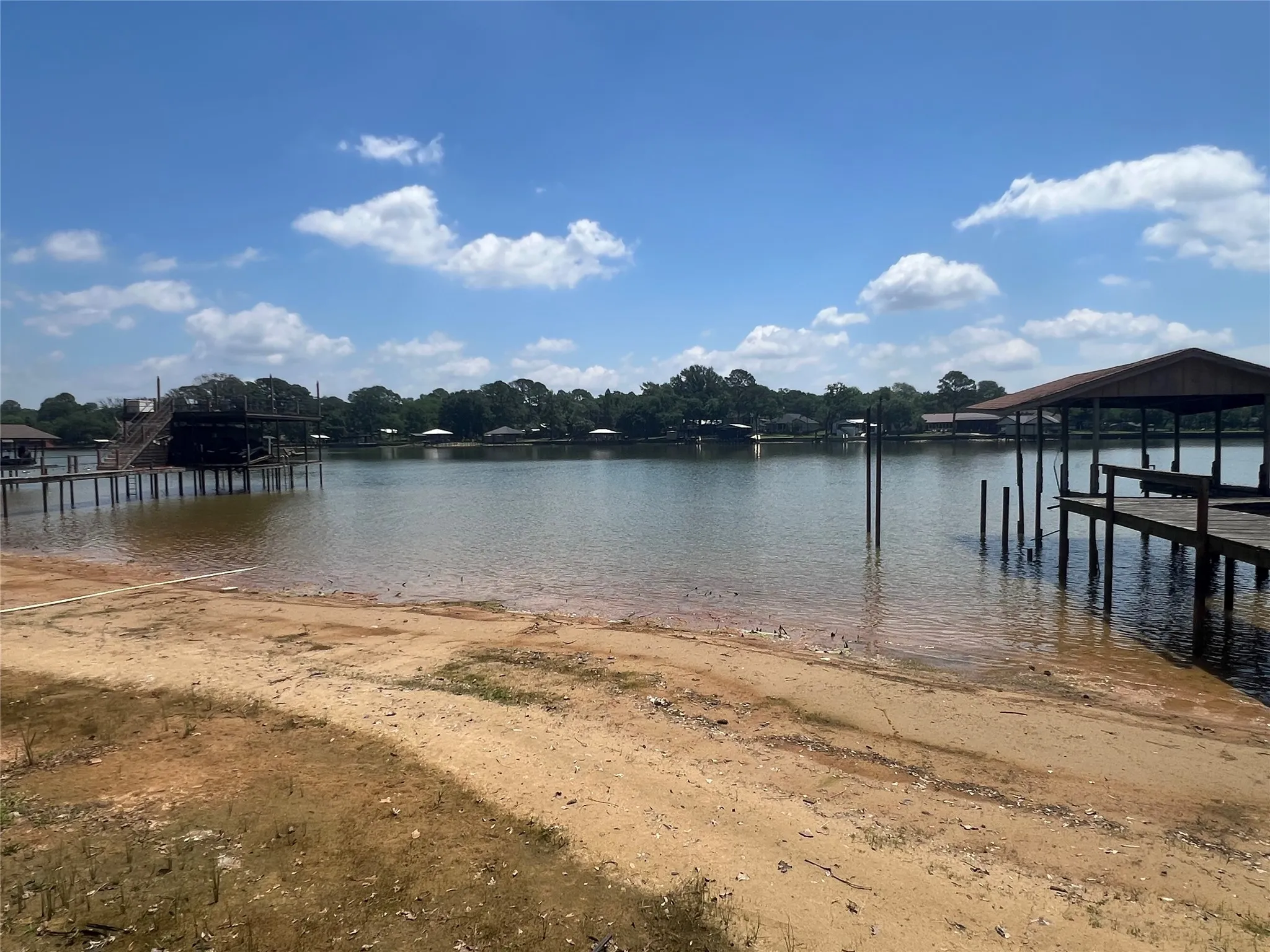 Expansive waterfront featuring a sandy shoreline, private covered boat dock, and additional boat lift structure