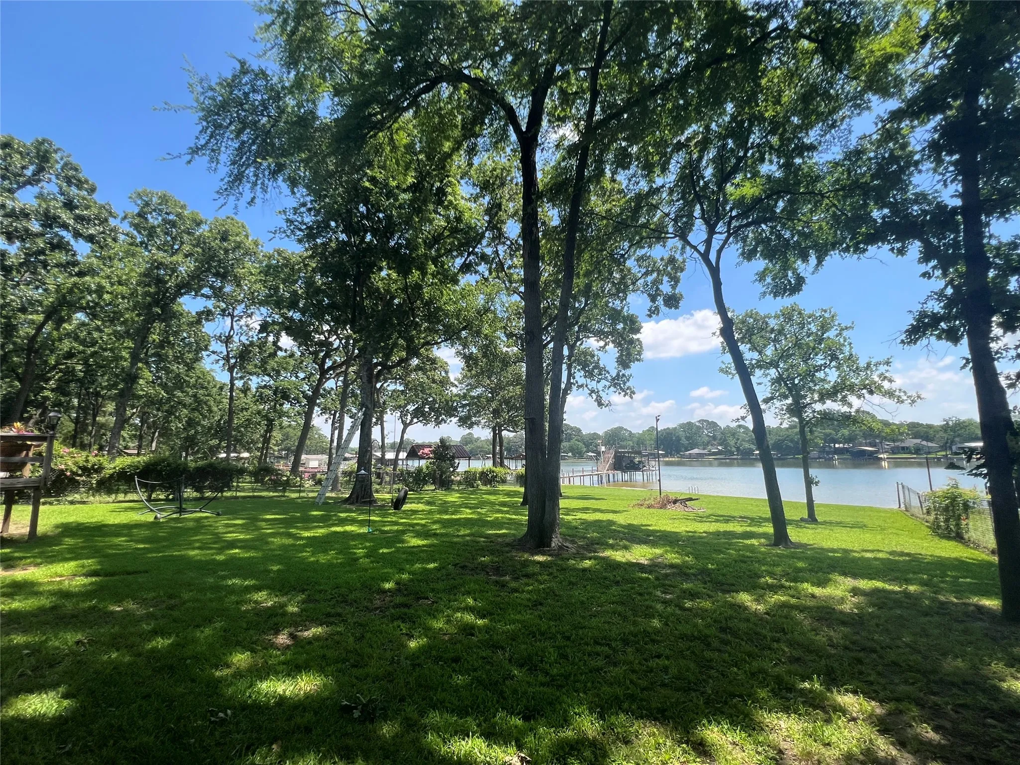 Expansive waterfront property featuring a gently sloping lawn and mature trees providing natural shade