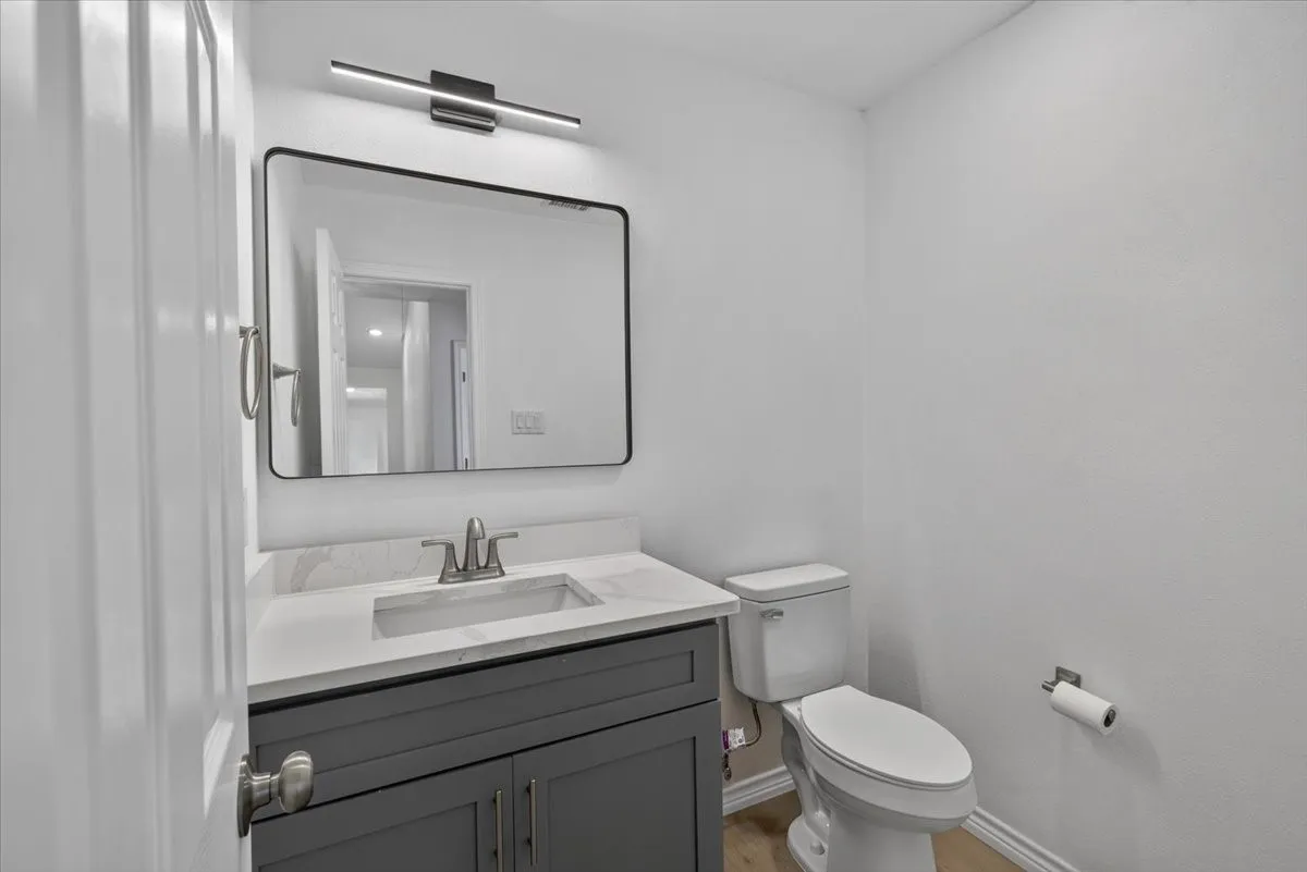 Bathroom featuring a dark gray vanity with a single sink, light-colored countertop, and a black-framed mirror