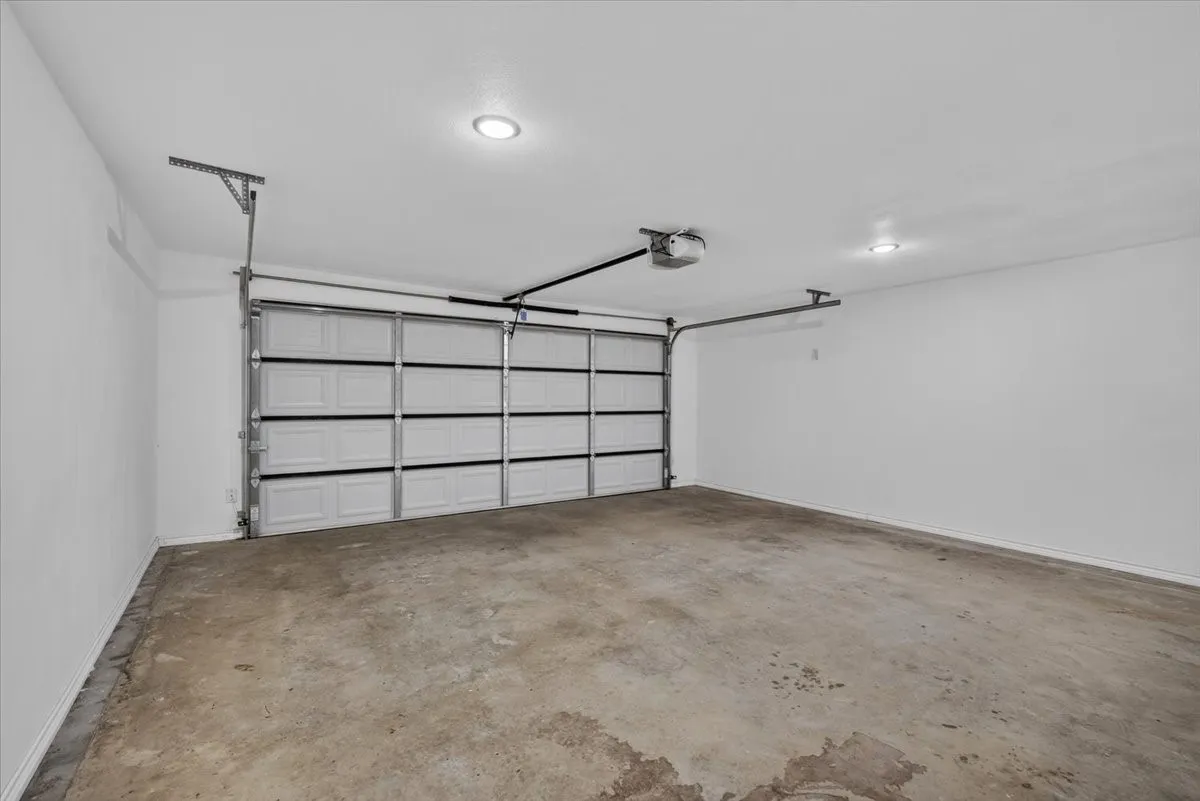 Spacious garage featuring a concrete floor, bright recessed lighting, and a paneled garage door with an automatic opener