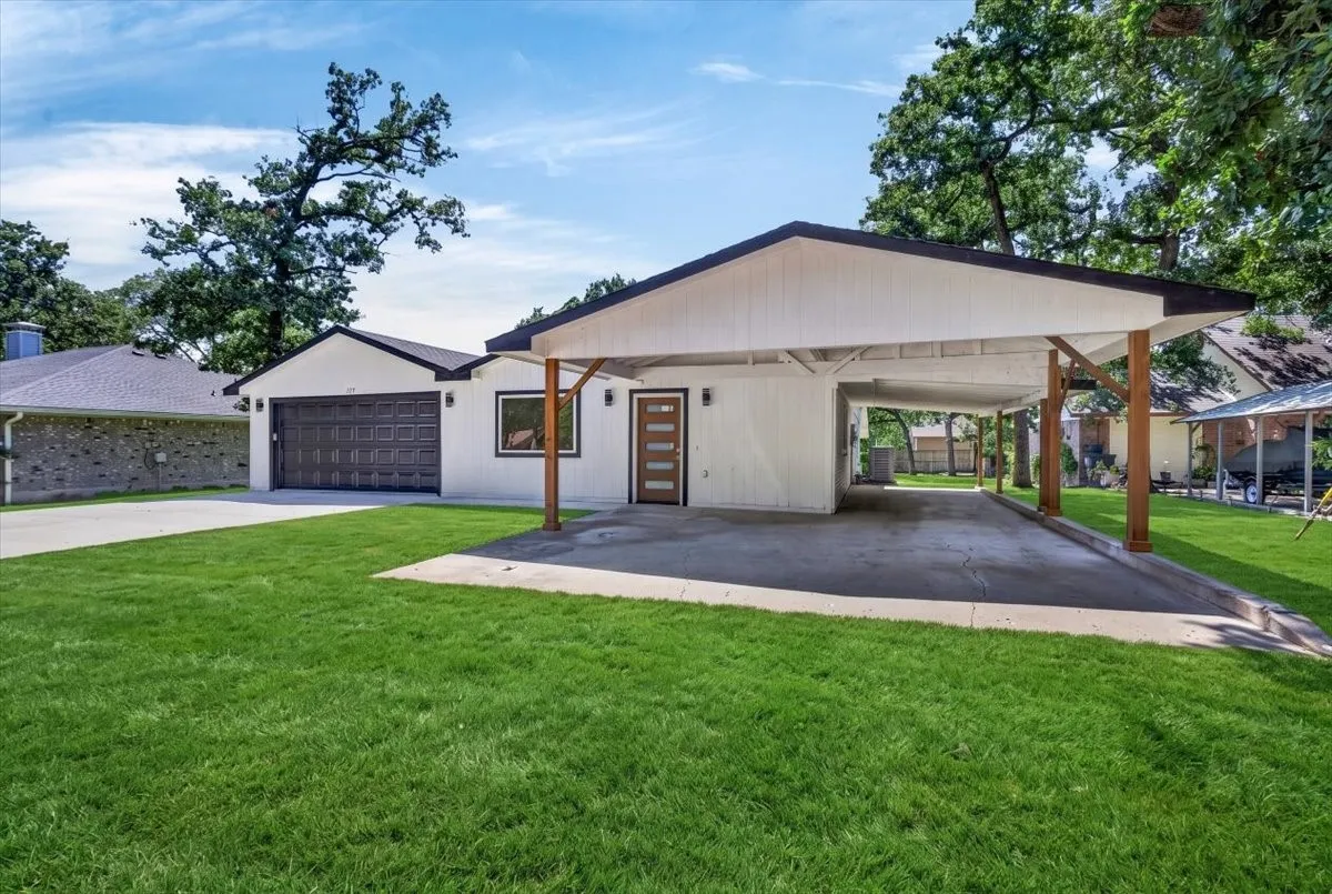 Modern exterior featuring white siding, a single-car garage with a dark panel door, and a covered carport with wood-finish support beams