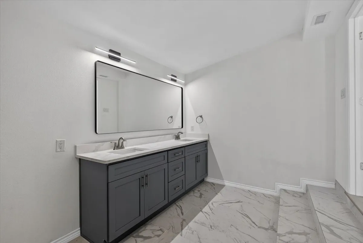 Double vanity featuring a light-toned countertop, dual rectangular undermount sinks, and a dark grey base with ample storage