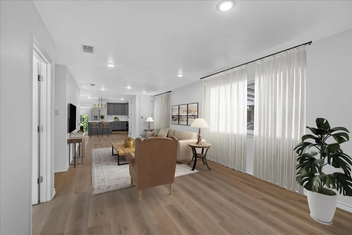 Open-concept living space featuring wood-finish flooring, recessed lighting, and large windows with sheer curtains
