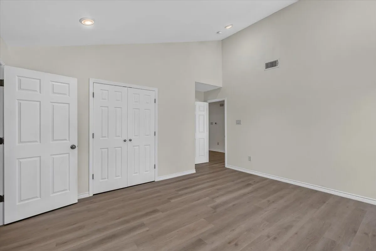 Spacious interior with vaulted ceilings, wood-finish flooring, recessed lighting, and a neutral color palette