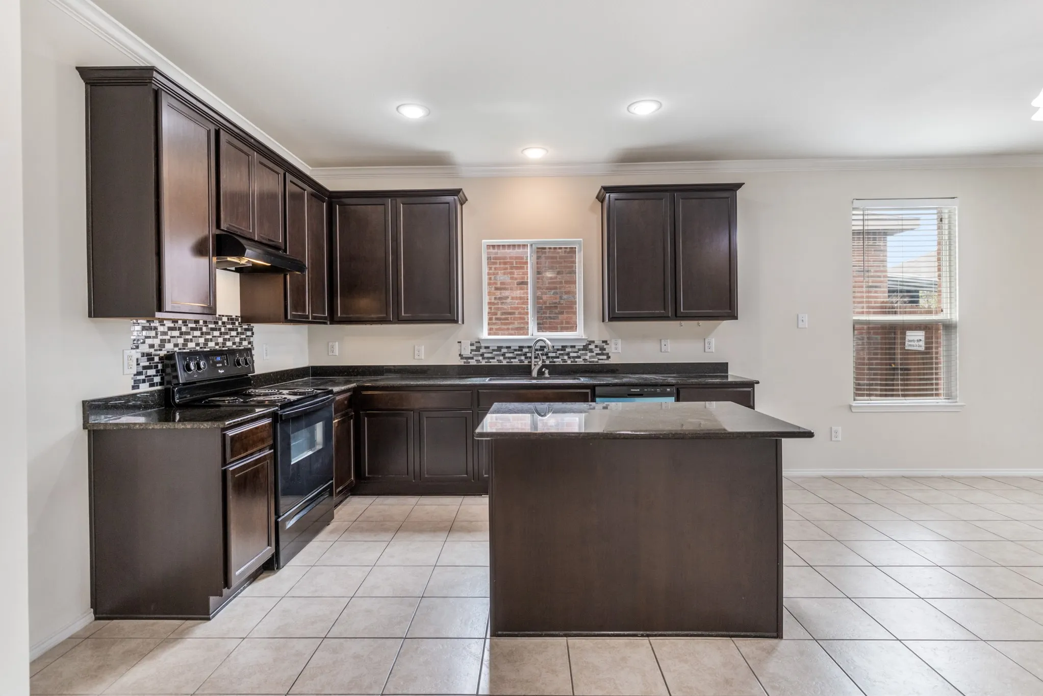 Kitchen featuring dark wood-finish cabinetry, dark countertops, and a mosaic tile backsplash