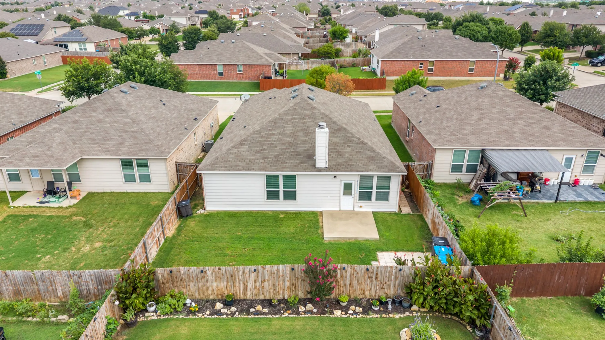 Backyard featuring a green lawn, concrete patio, and perimeter wood fencing