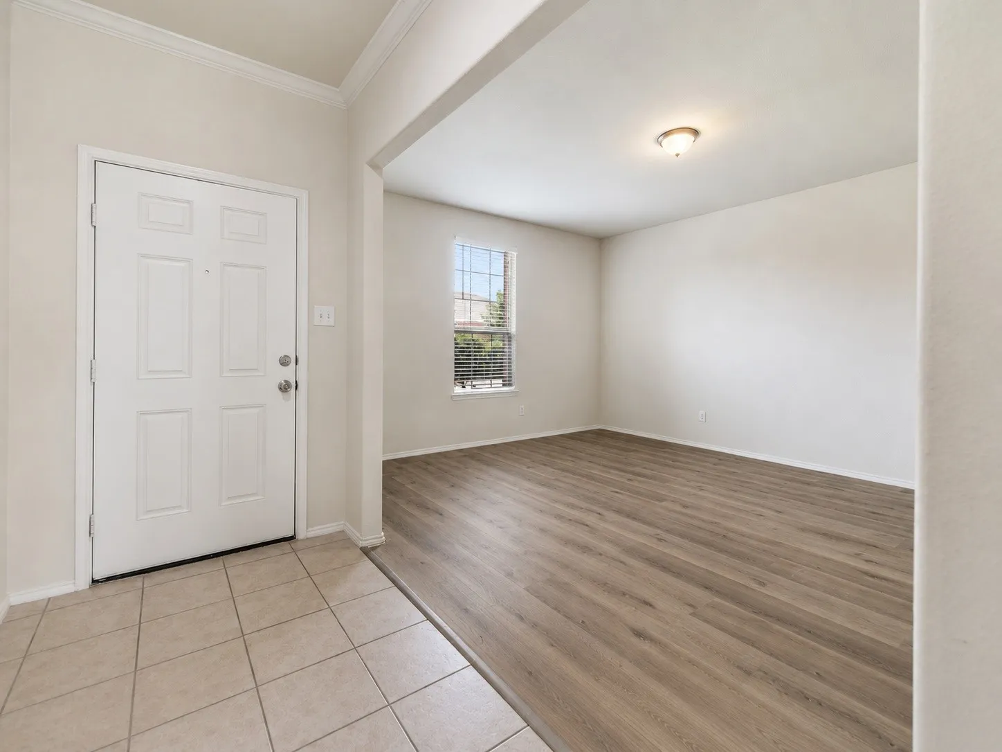 Entryway featuring ceramic tile flooring, a paneled door, and crown molding