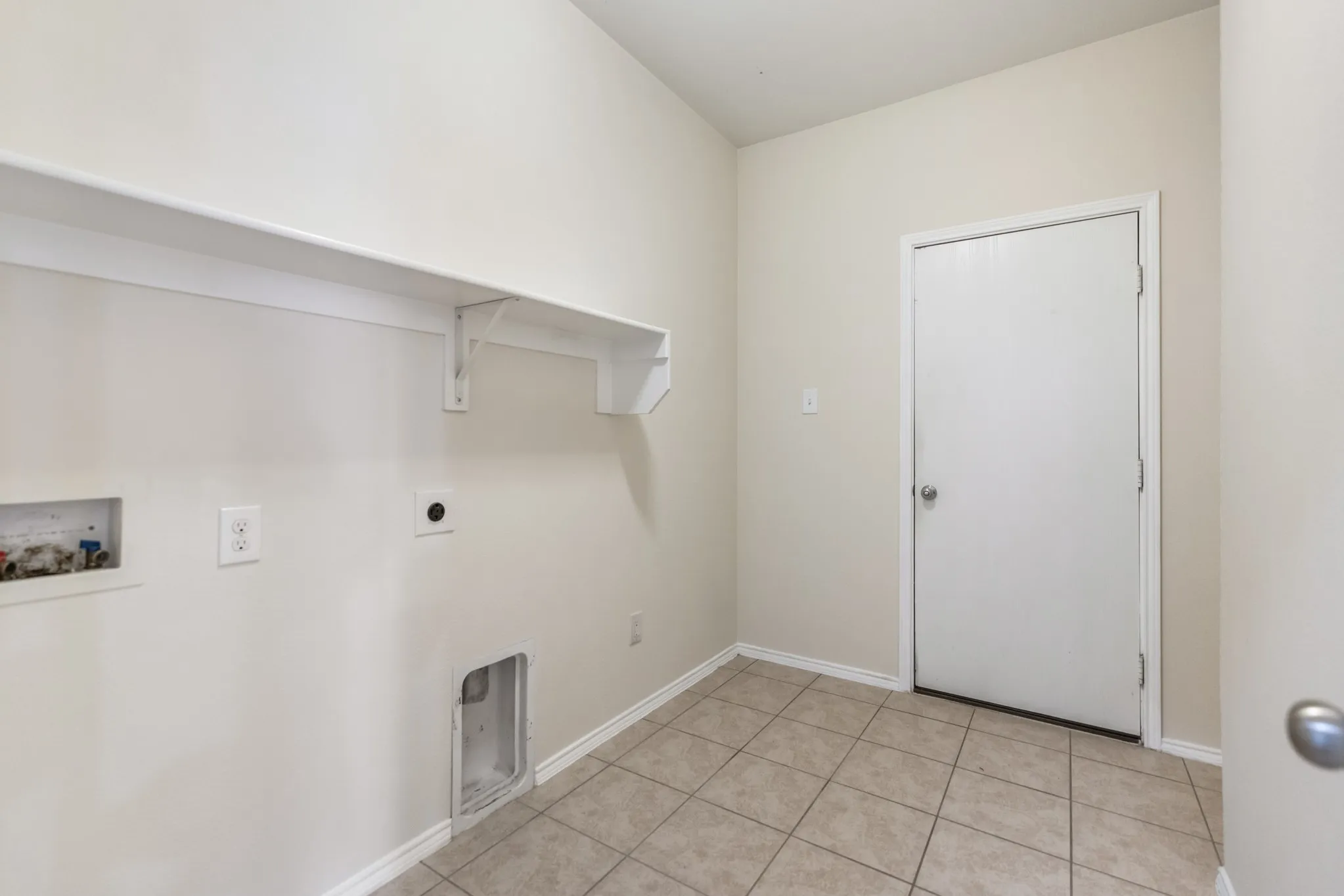 Utility room with neutral tile flooring and light-toned wall paint