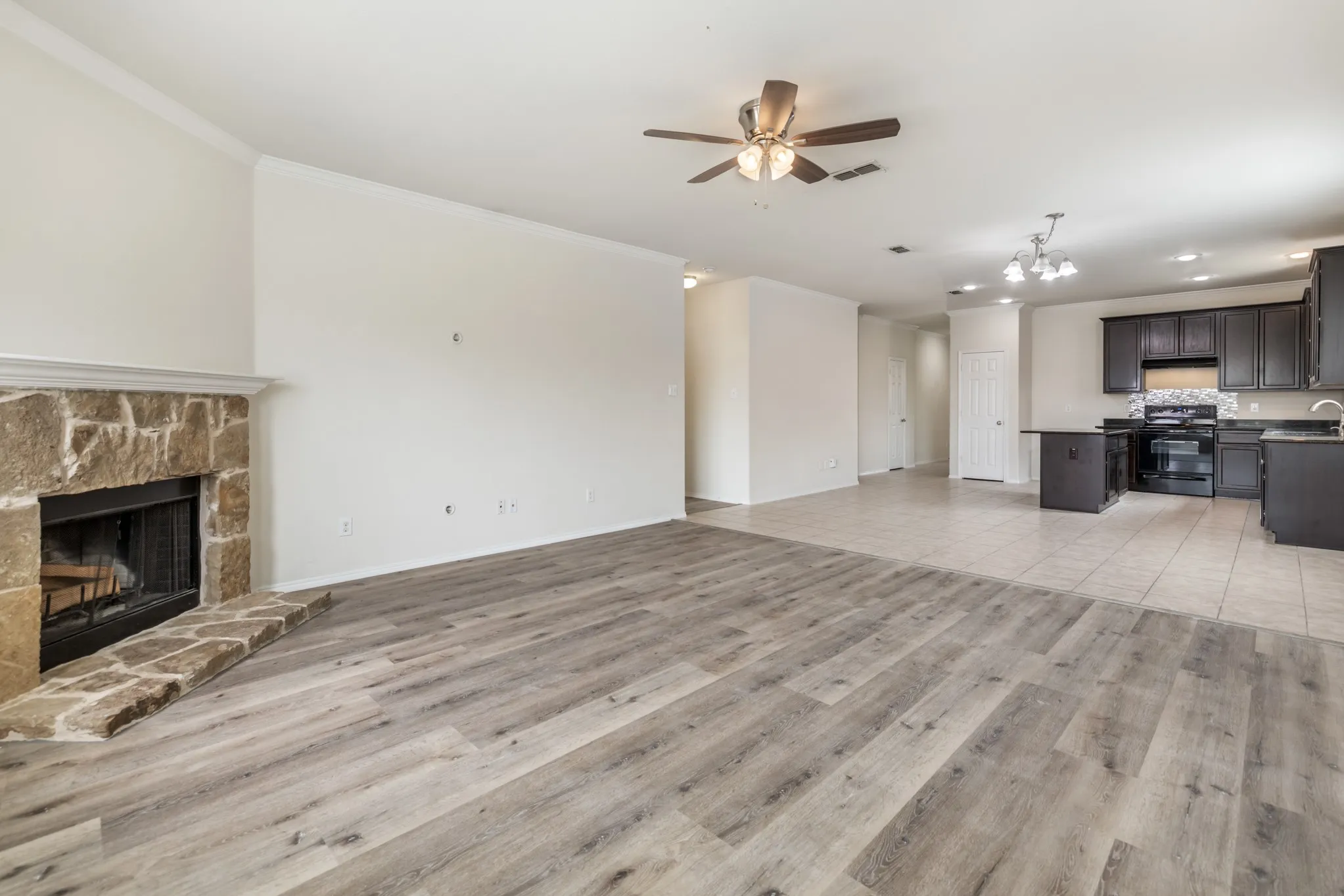 Spacious living area featuring wood-finish flooring and a stone-clad fireplace