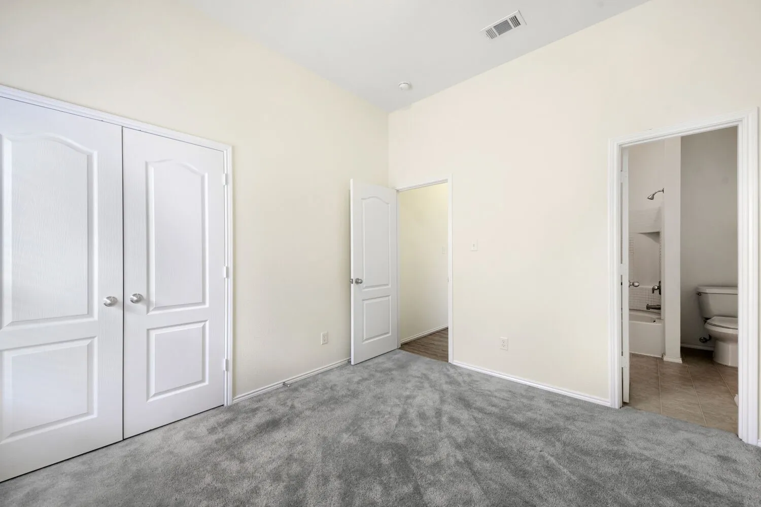 Carpeted room featuring a double-door closet, vaulted ceiling, and white trim