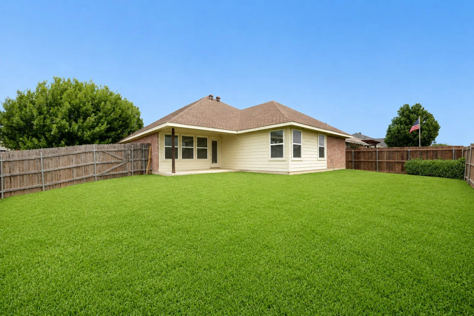 Expansive backyard featuring a manicured lawn, full wood privacy fencing, and mature perimeter trees