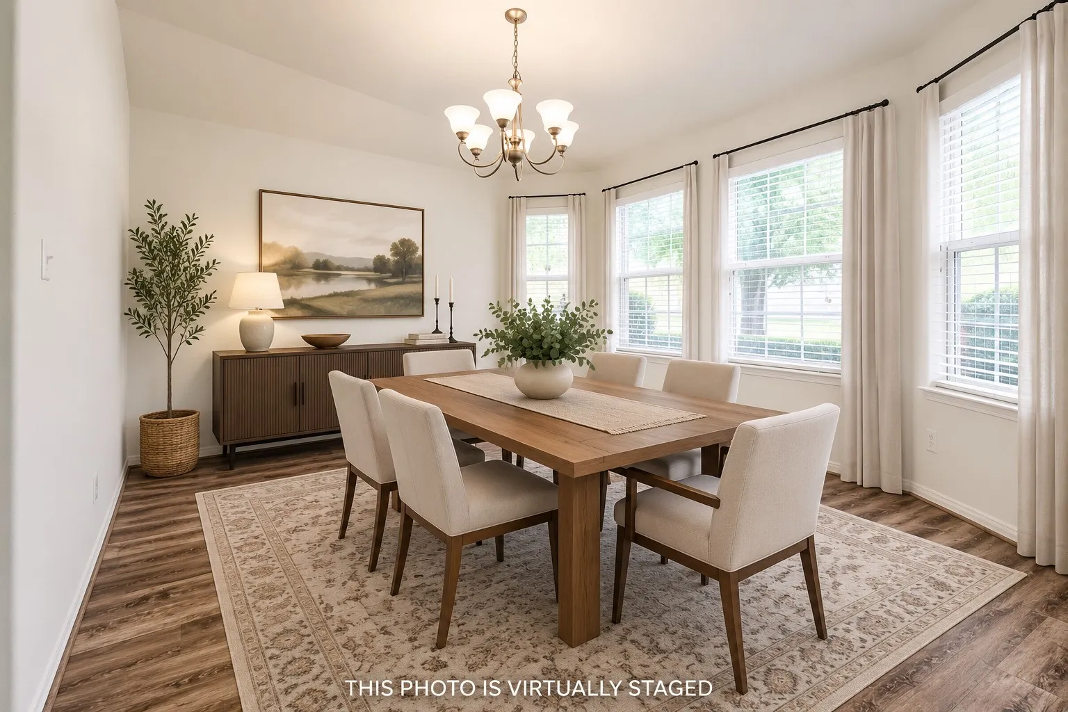 Dining area featuring wood-finish flooring, a contemporary chandelier, and a bay window configuration with multiple windows. (Virtual staged with furniture and drapes, blinds are real.)