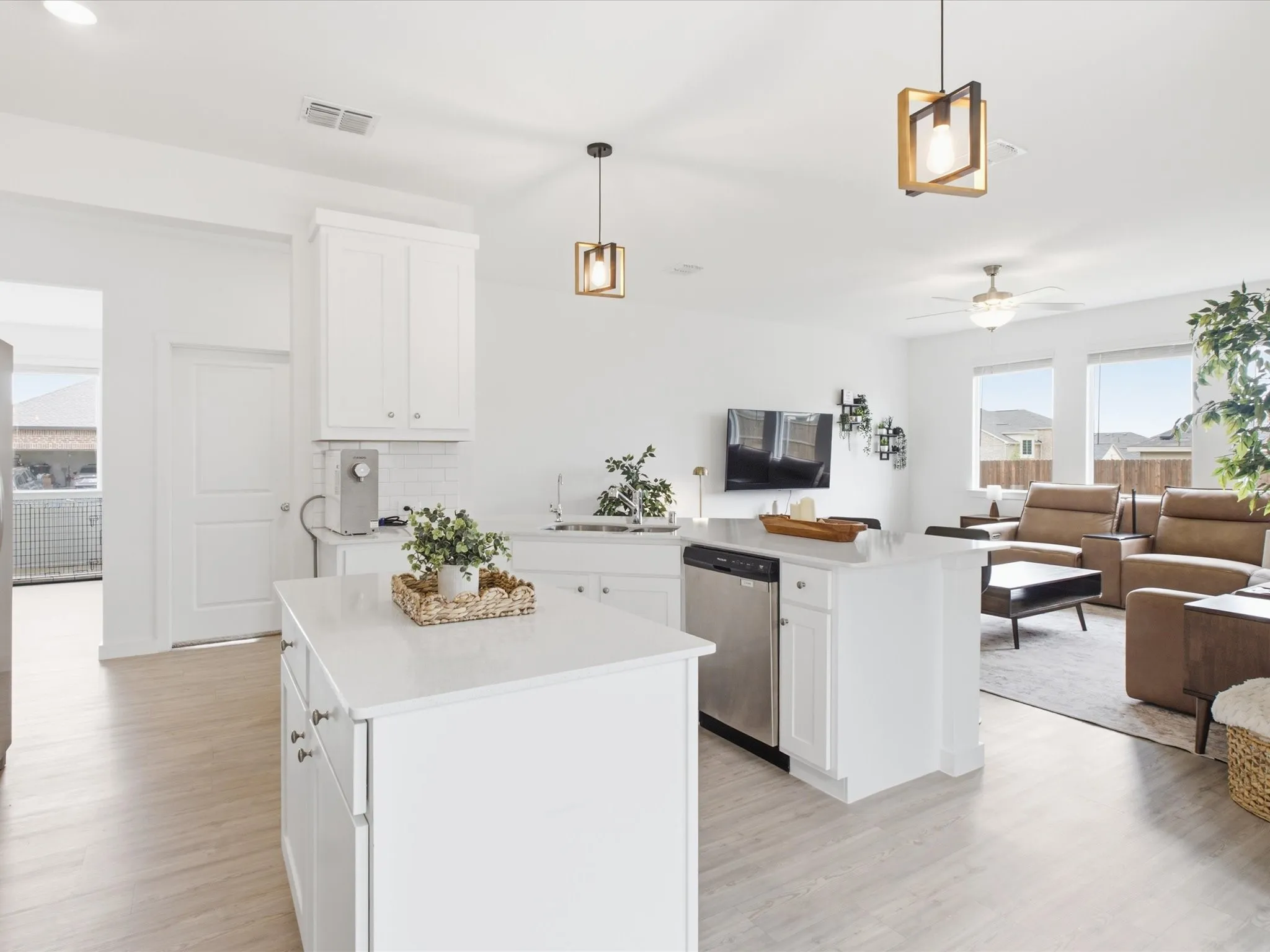 Open-concept kitchen featuring an island with a light-toned countertop, white cabinetry, and stainless steel appliances