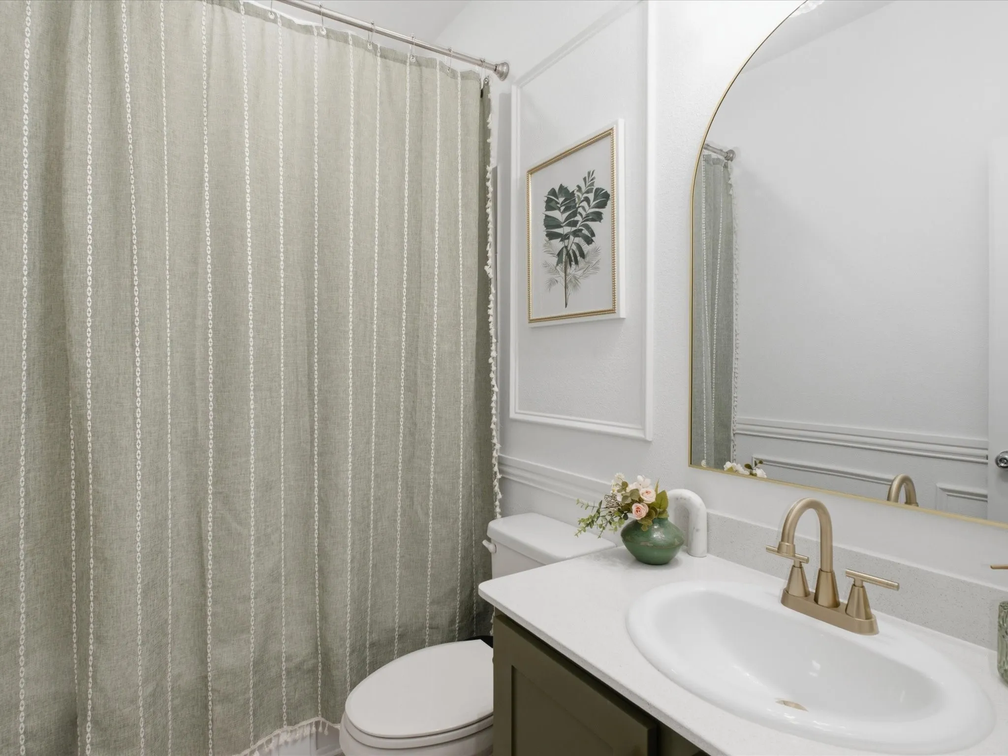 Bathroom featuring a vanity with an oval undermount sink, a gold-toned faucet, and a light-colored countertop