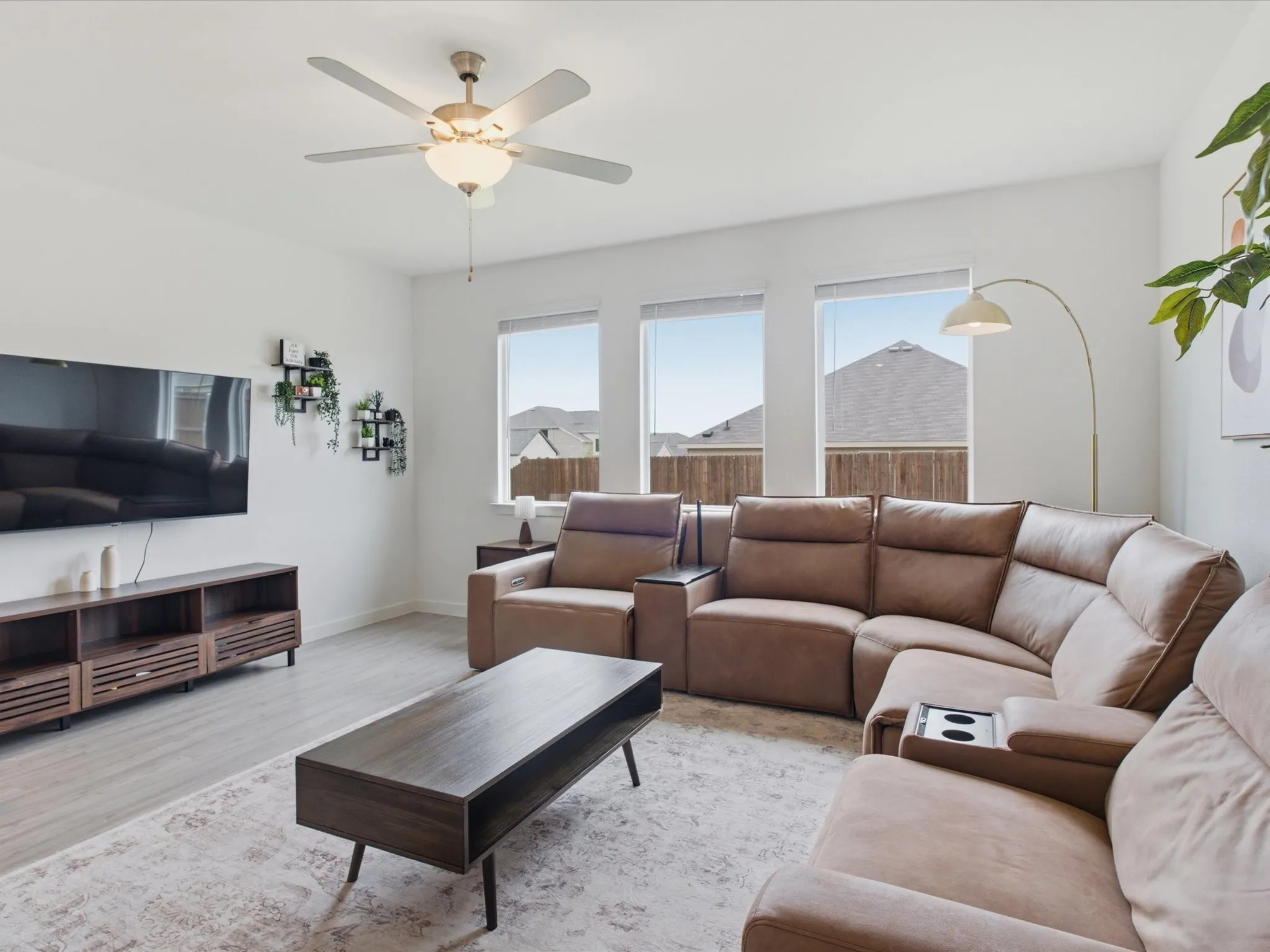 Living area with light wood-finish flooring and a ceiling fan with integrated lighting