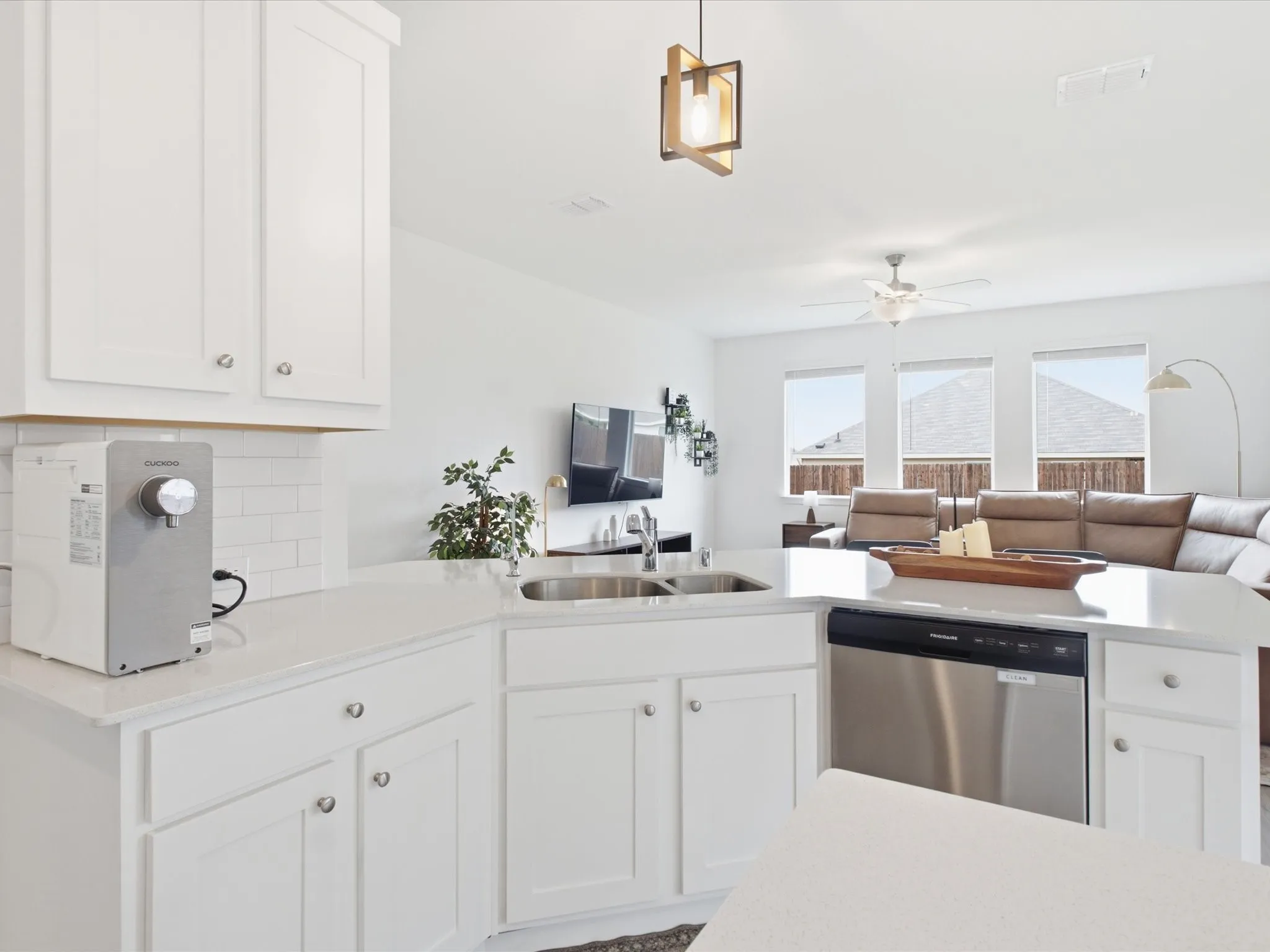 Open-concept kitchen featuring white shaker cabinetry, light countertops, subway tile backsplash, and a stainless steel dishwasher