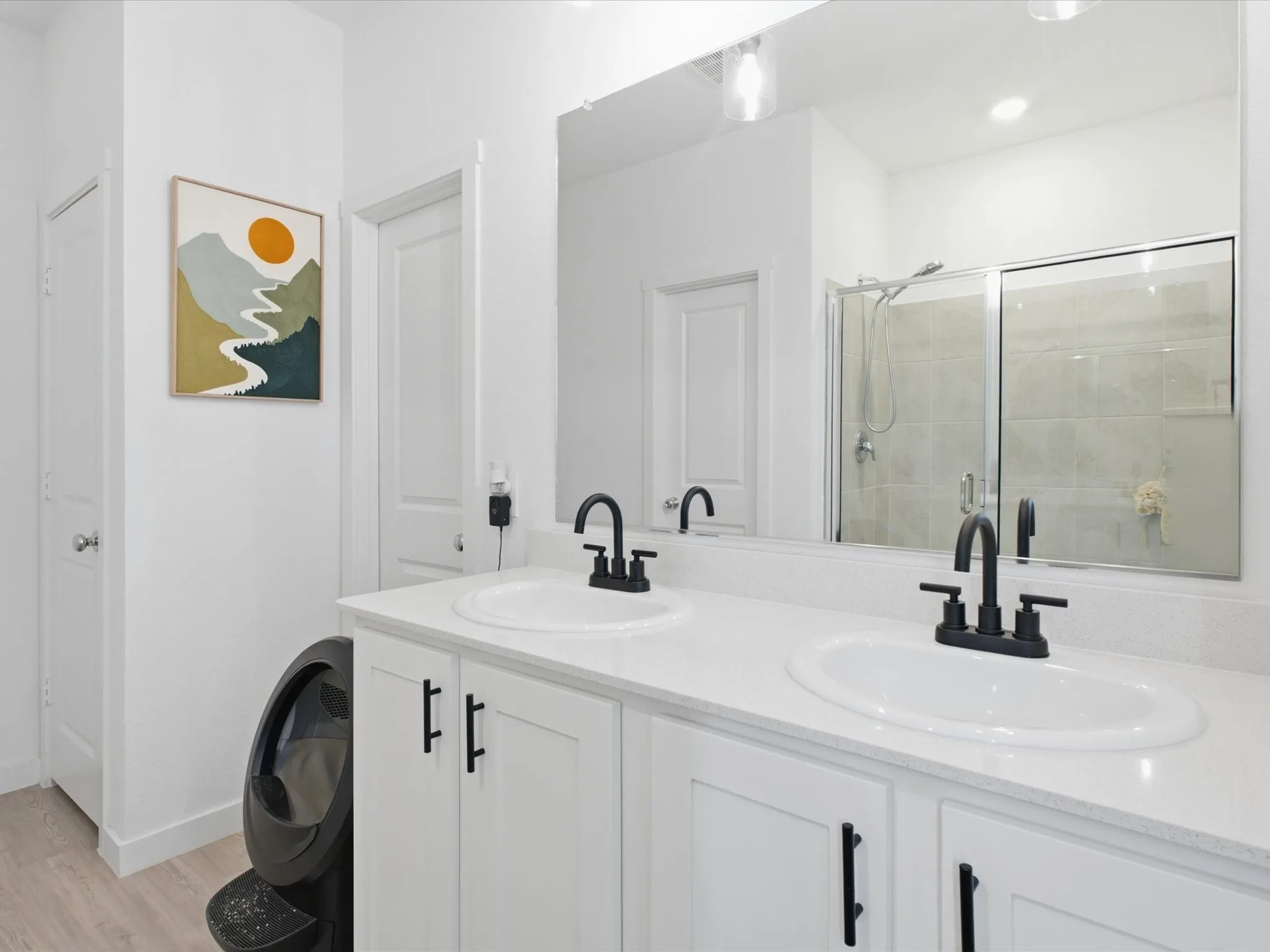 Bathroom featuring a dual vanity with white cabinetry, white countertops, and matte black hardware