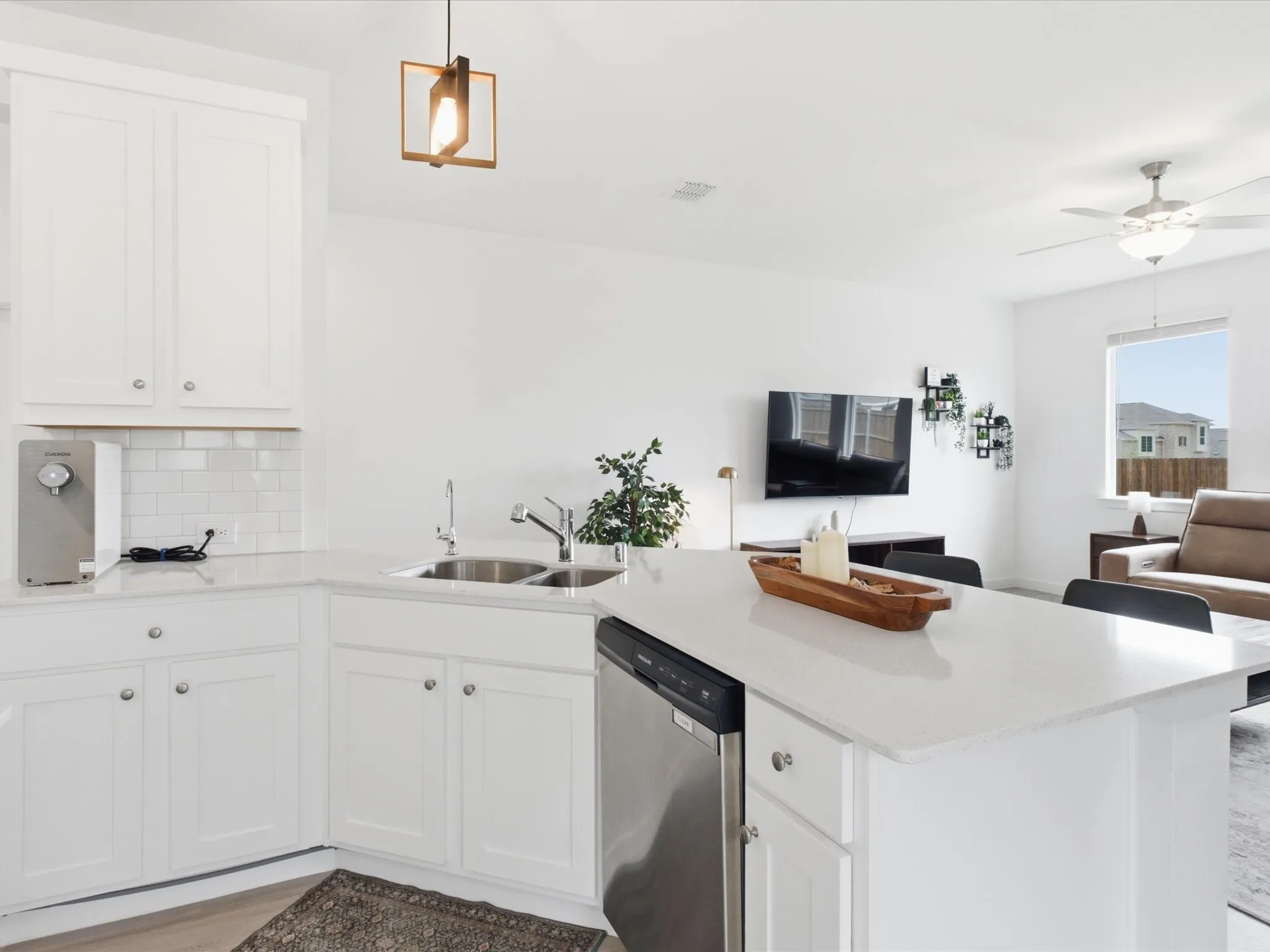 Kitchen featuring white shaker cabinetry, light-toned countertops, a stainless steel double-basin sink, and a subway tile backsplash