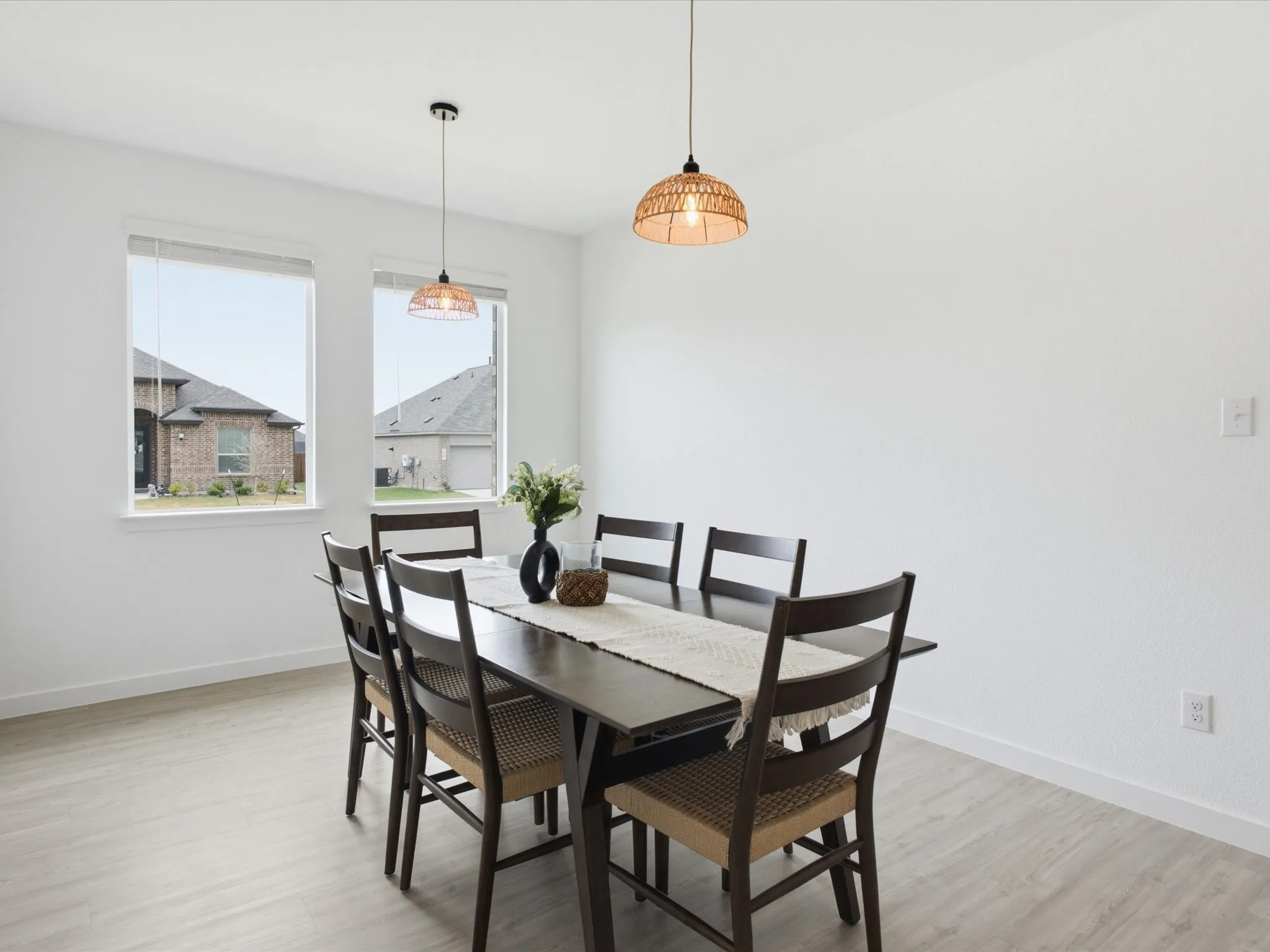 Bright dining area featuring two windows, light wood-finish flooring, and white walls