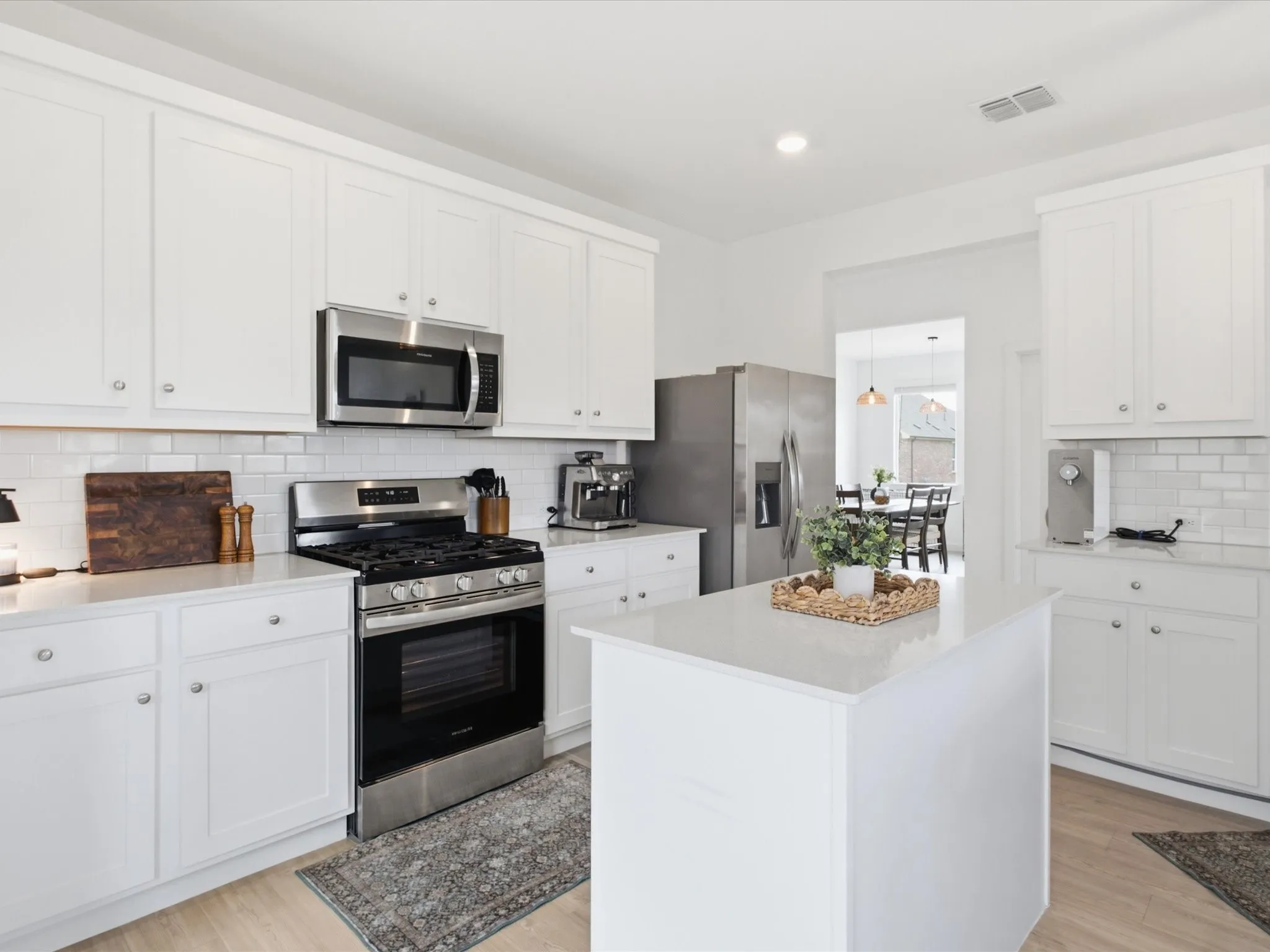 Contemporary kitchen featuring white cabinetry, subway tile backsplash, stainless steel appliances, and a central island with a solid surface countertop