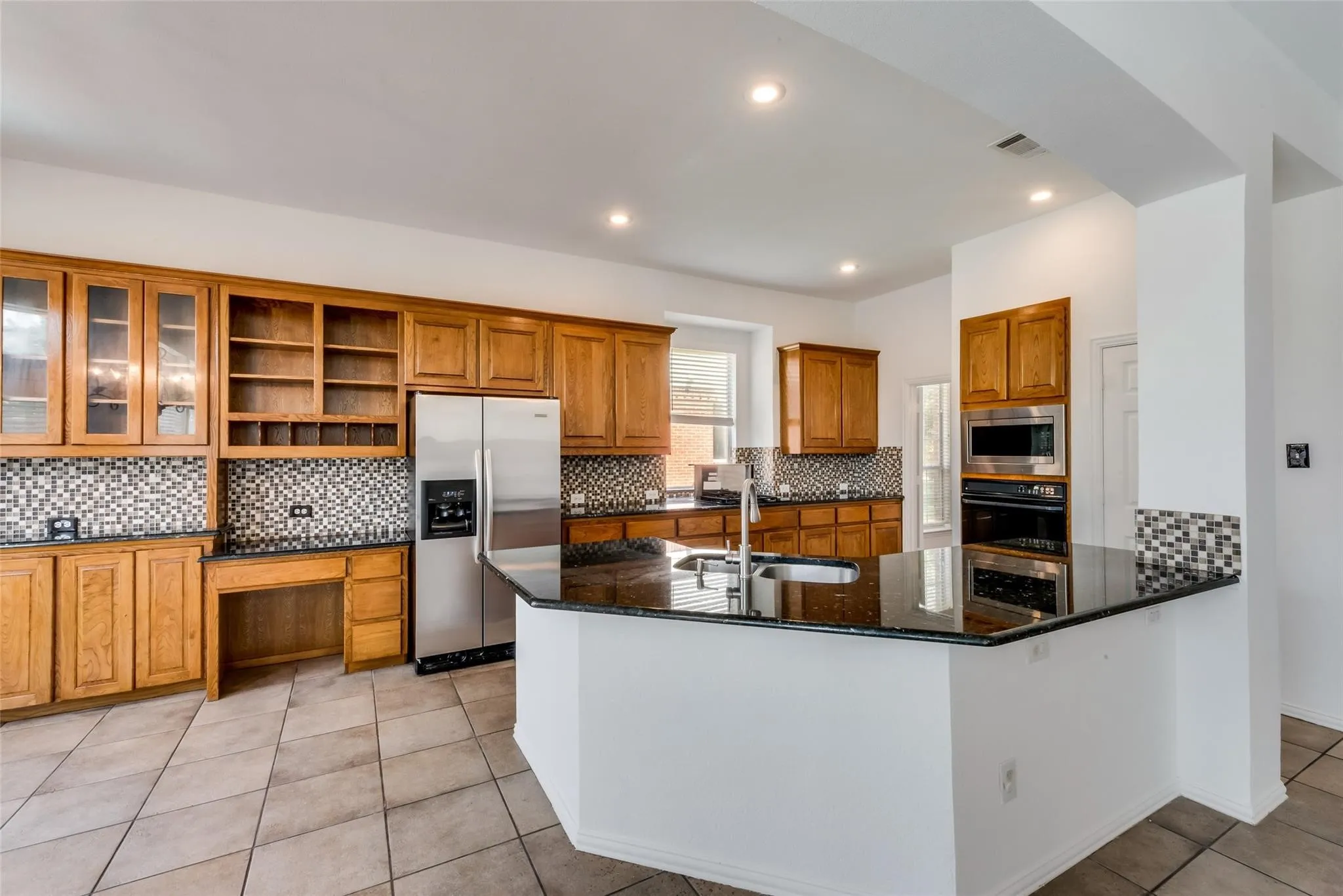 Kitchen featuring an island with a black stone countertop and stainless steel sink