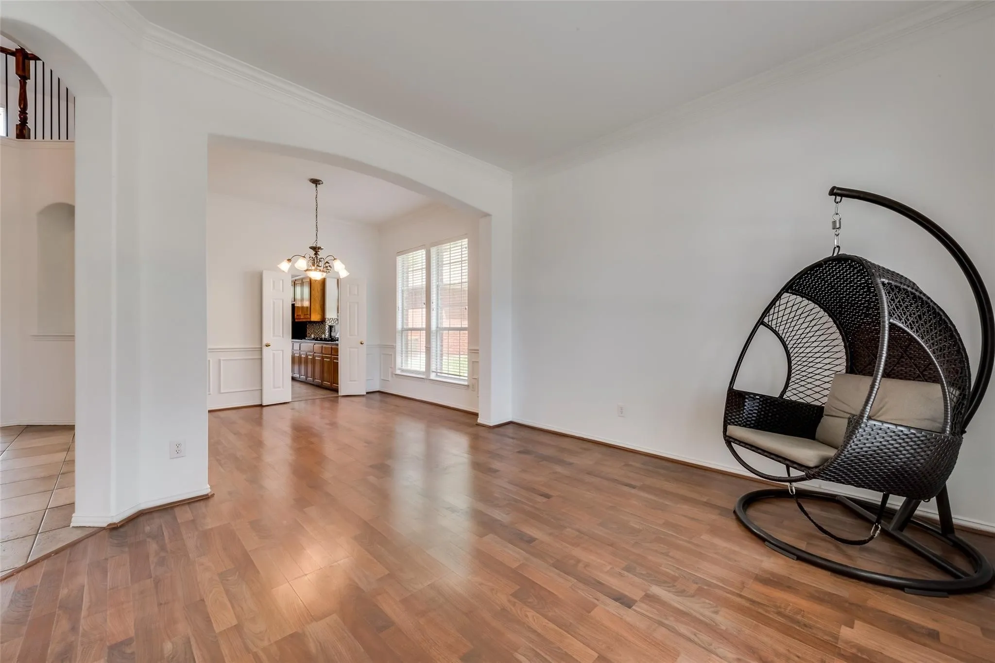 Hardwood-finish flooring throughout, featuring a broad arched entryway, crown molding, and wainscoting