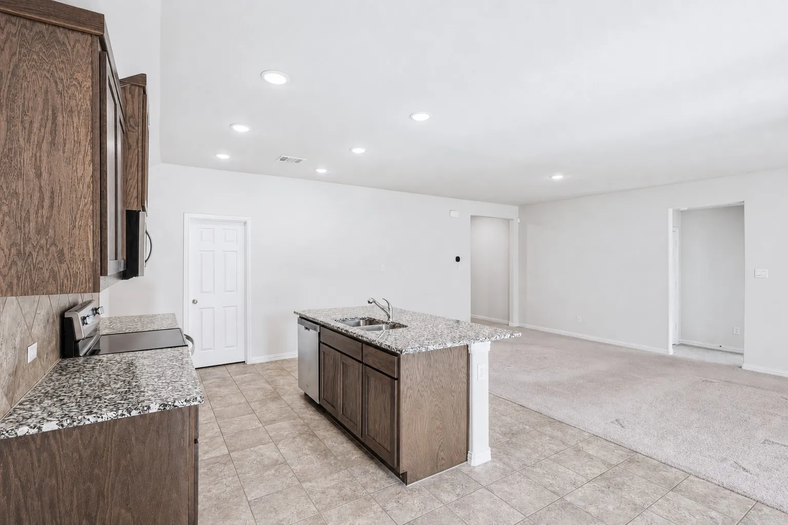 Kitchen featuring a central island with dual sinks, stone countertops, and dark wood-finish cabinetry