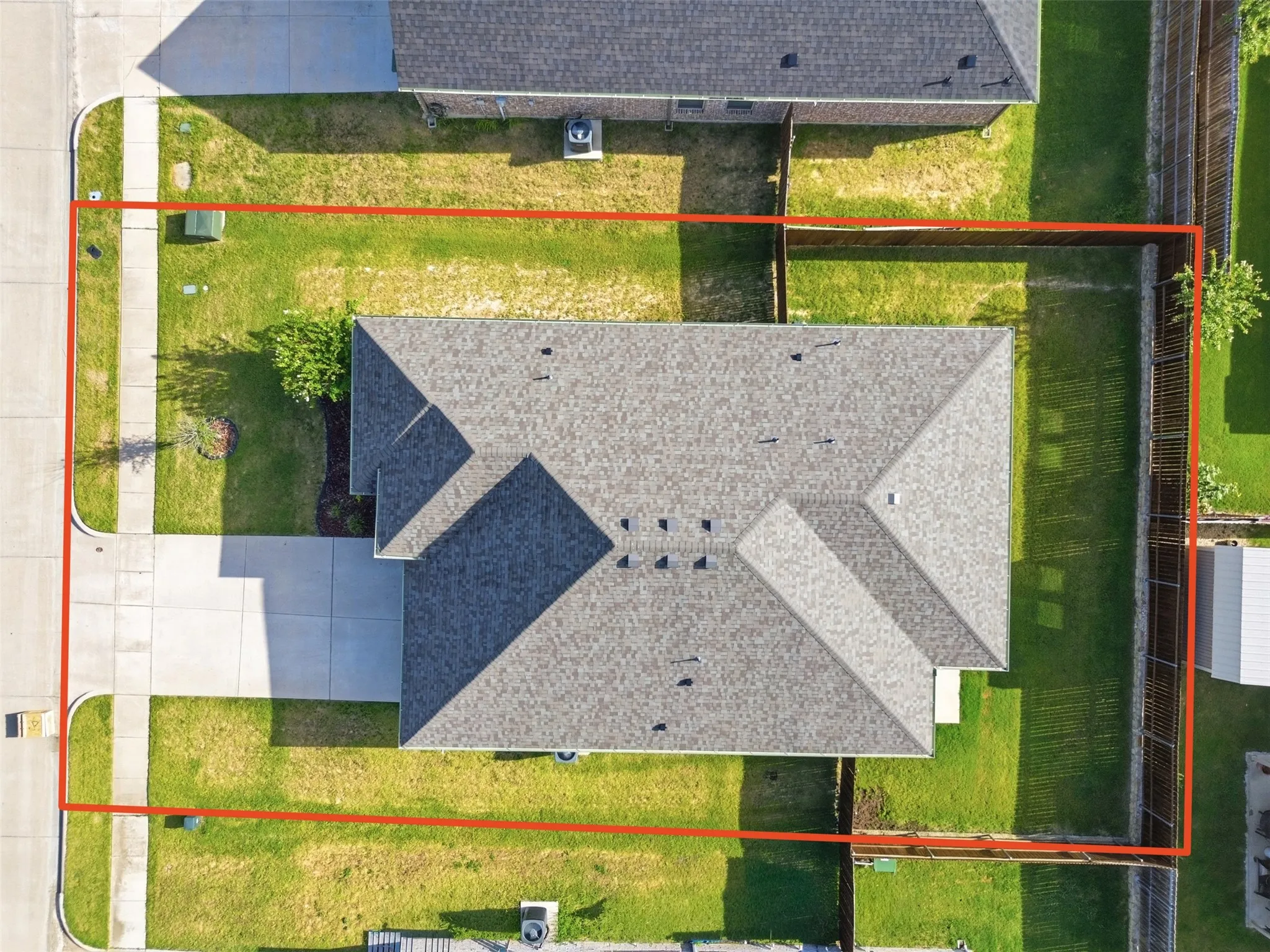 Aerial perspective showcasing the property's perimeter, featuring a gabled roofline, concrete driveway, and surrounding green space