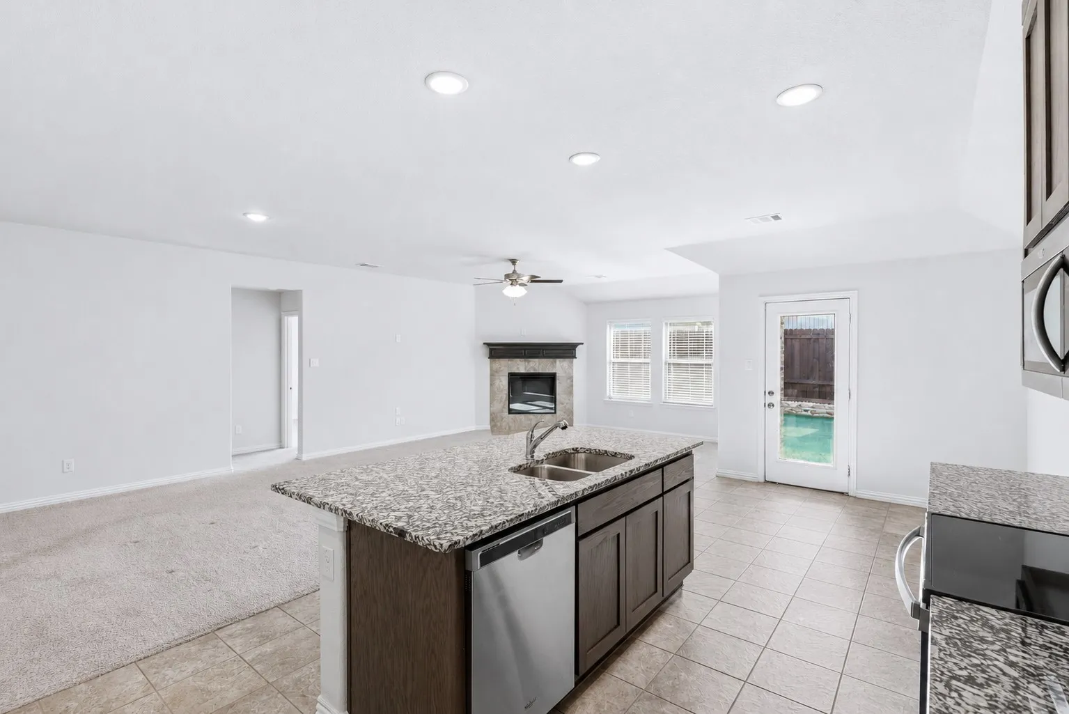 Central kitchen island featuring a dual-basin sink, granite countertop, and stainless-steel dishwasher