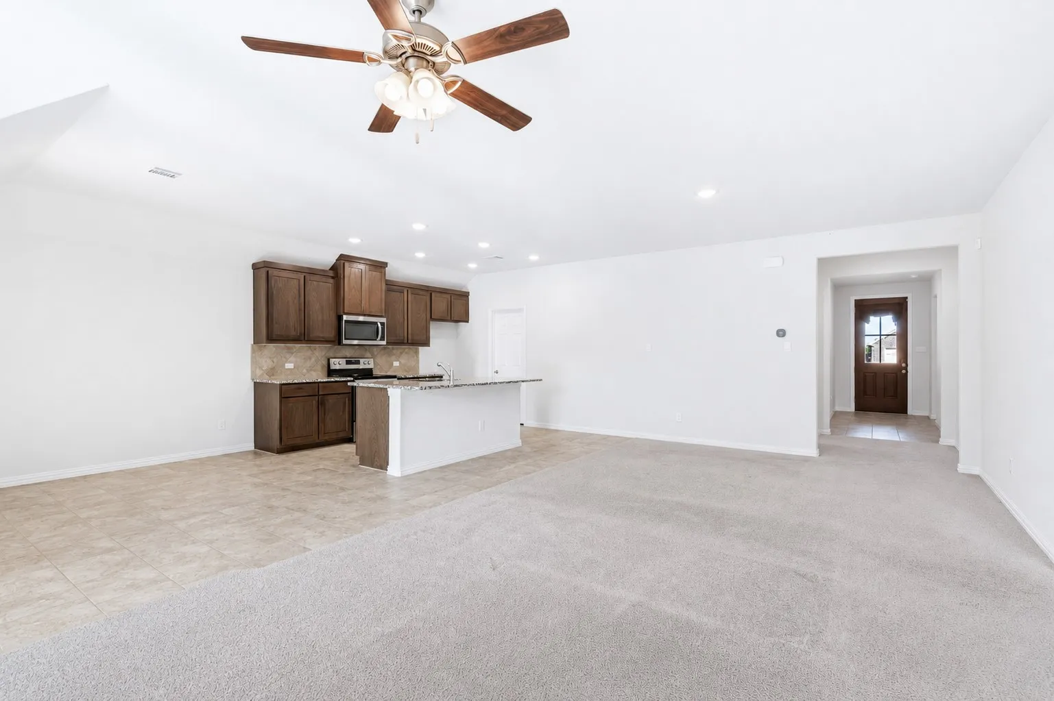 Open concept living area featuring a kitchen island with a breakfast bar, recessed lighting, and a ceiling fan