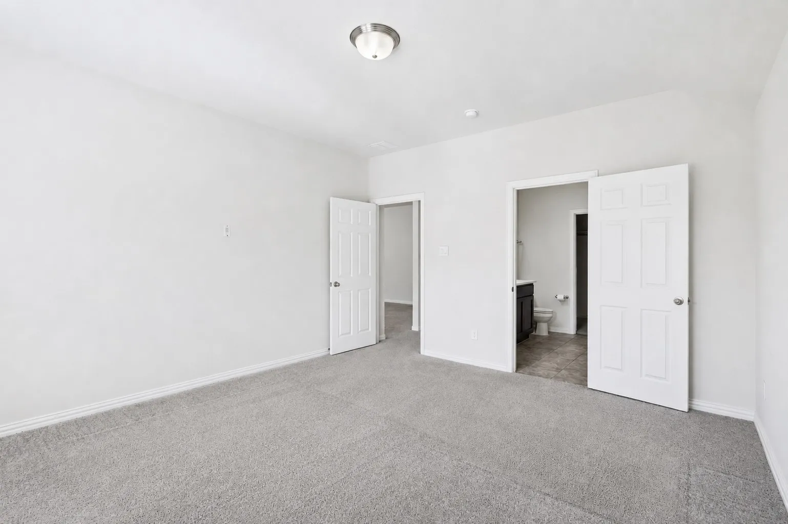 Spacious room featuring light gray carpeting, white painted walls, and white trim
